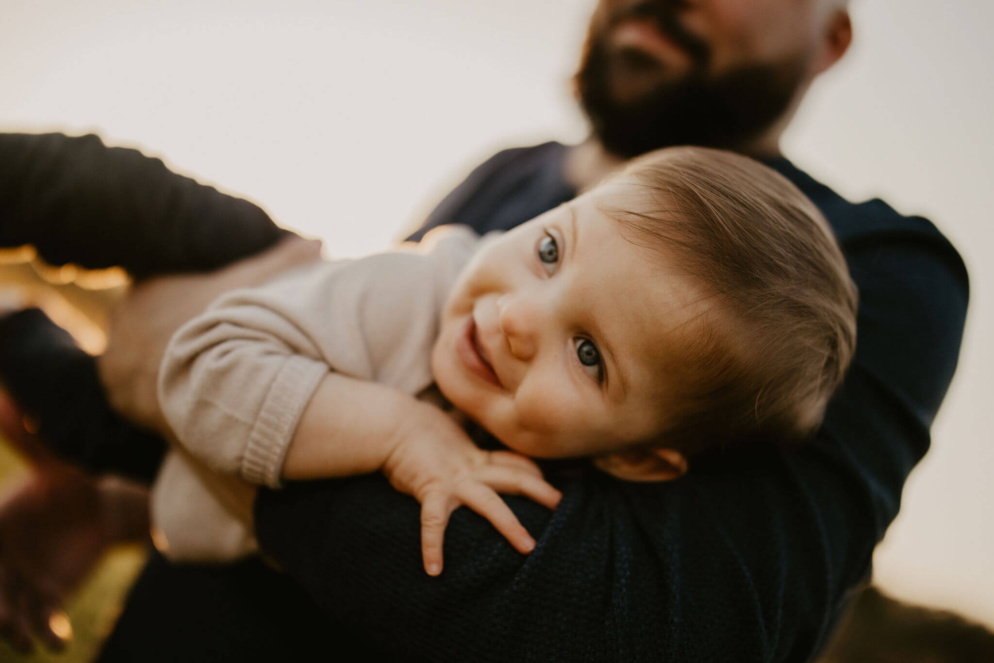 a young boy smiling in his father's arms during a family session