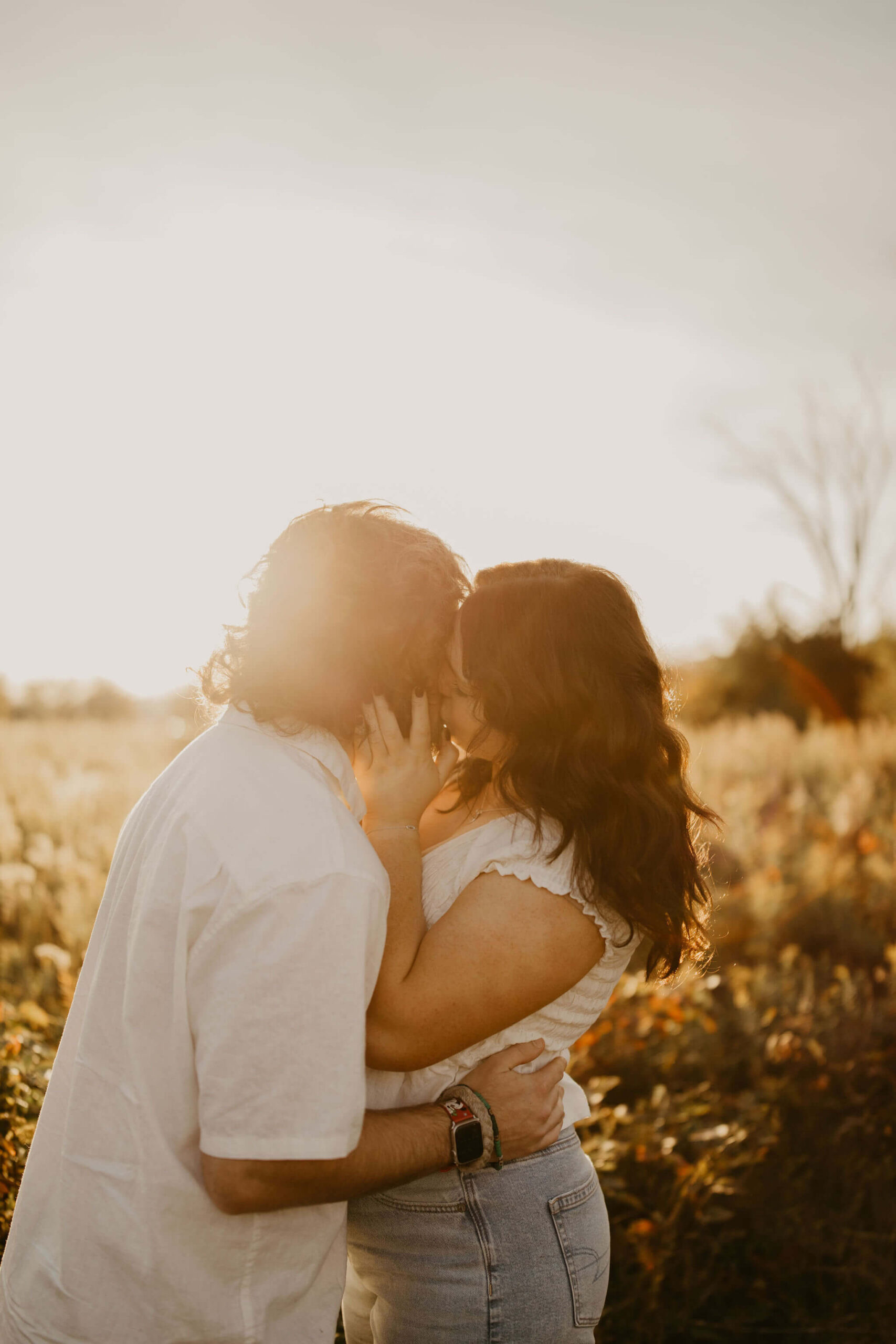 a couple embracing and kissing at sunset in a field in a park in Bucks County, Pennsylvania
