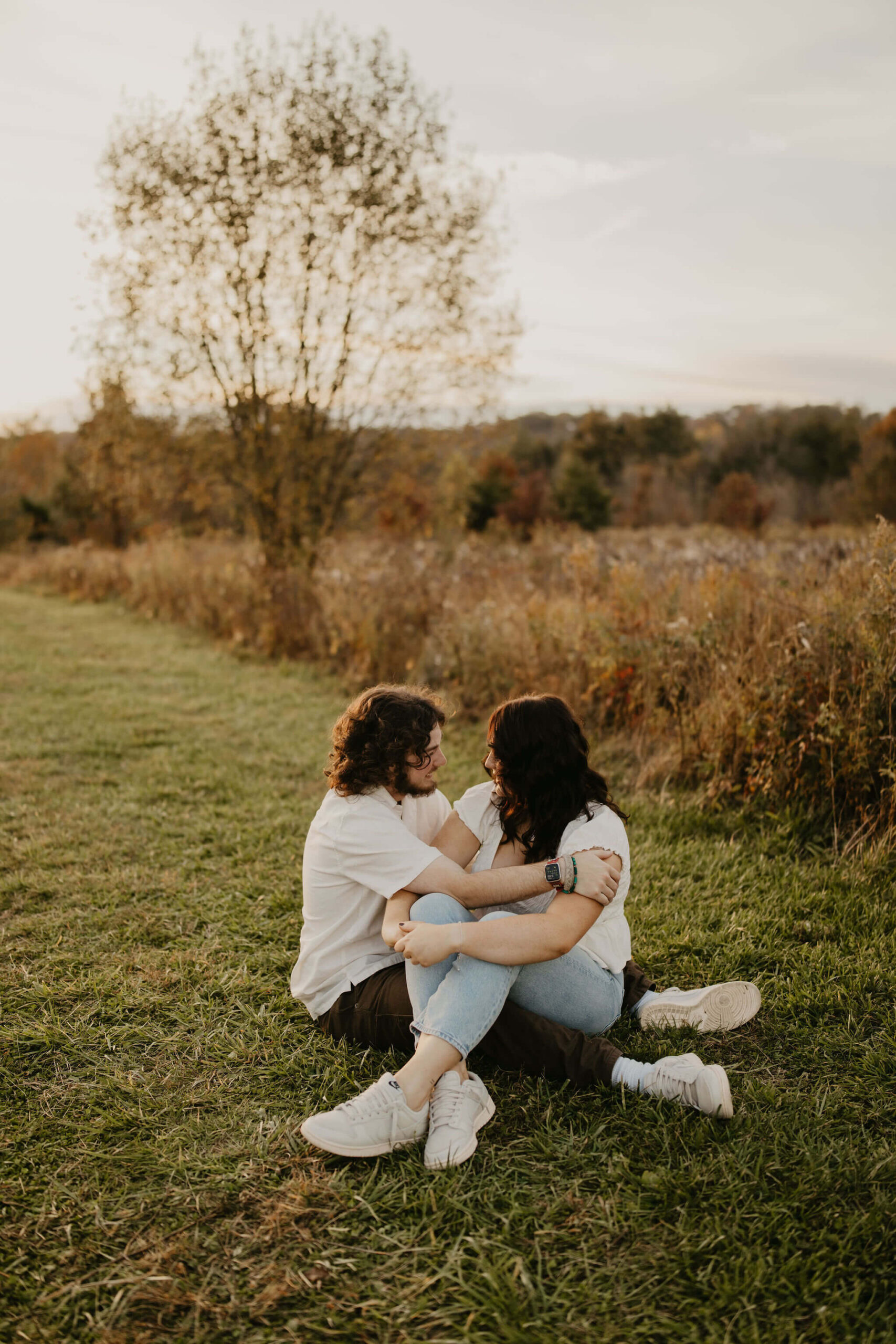 a boy and a girl sitting on the ground in a field smiling at each other at a park in Bucks County, Pennsylvania