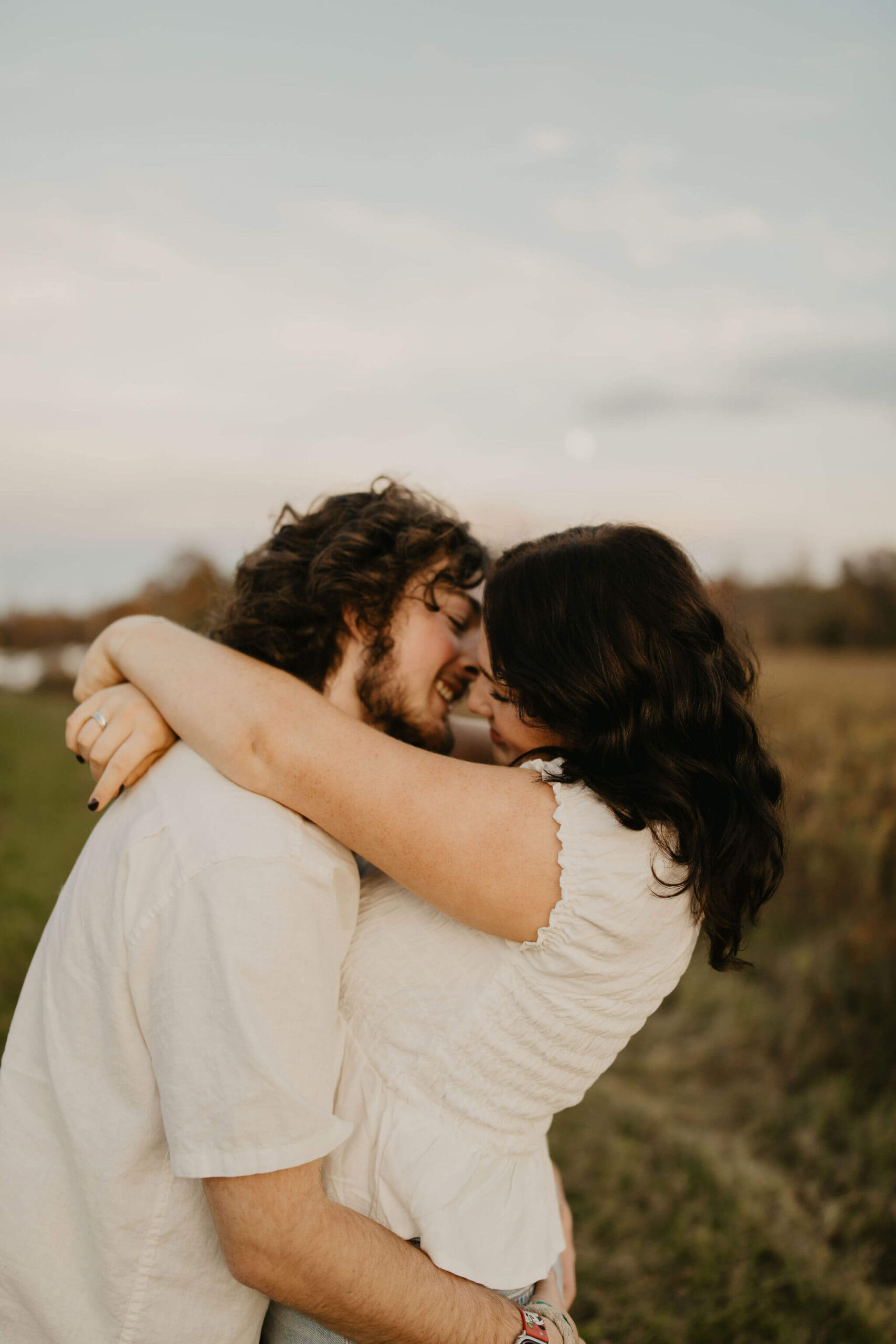 a couple about to kiss, smiling at each other and embracing in a field in doylestown pa