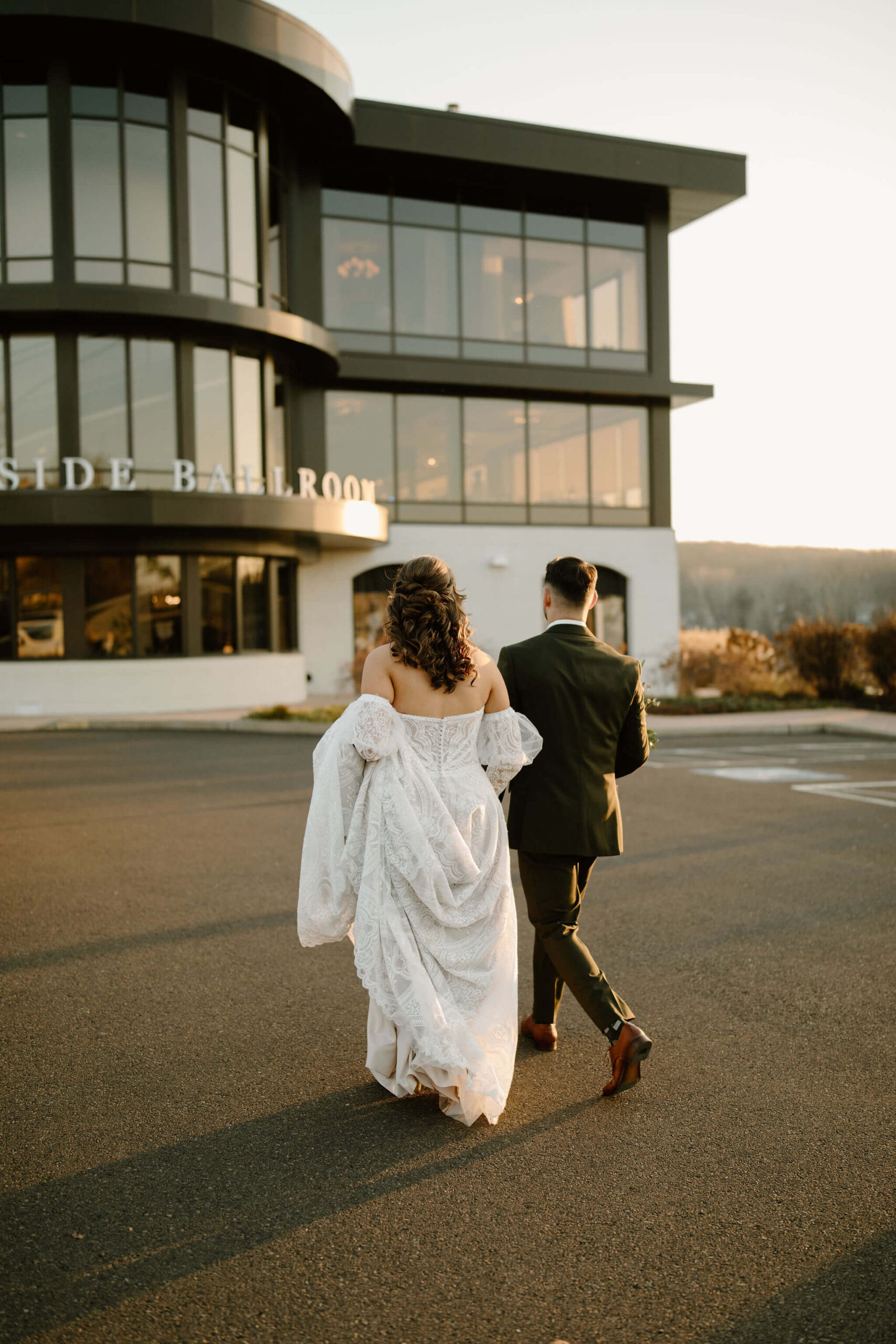 bride and groom walking away from the camera toward their wedding venue in lambertville new jersey at sunset