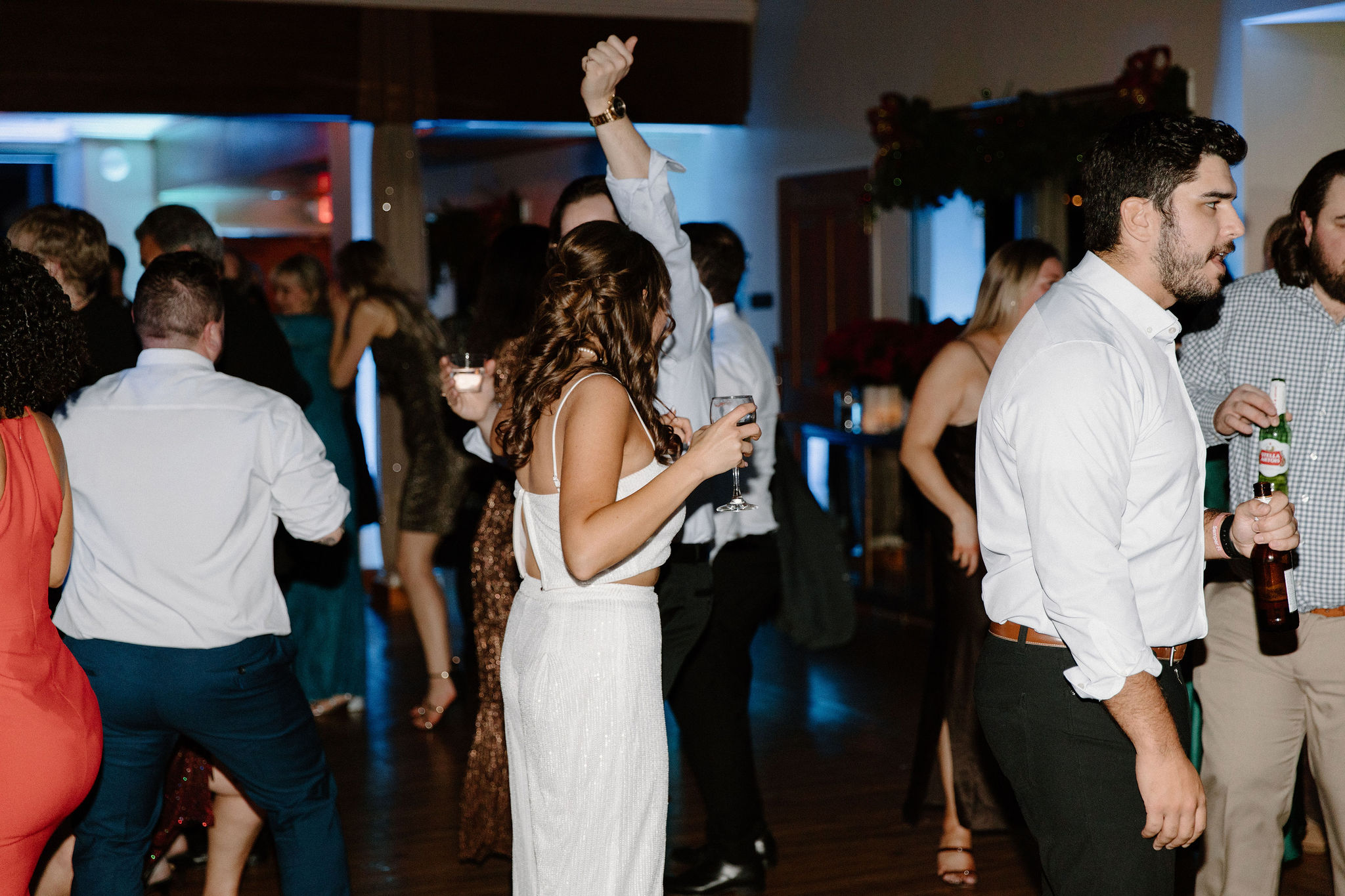 bride (brown hair, white sparkly tank top and sparkly flowy pants) holding a glass of champagne and dancing during a wedding reception in lambertville new jersey
