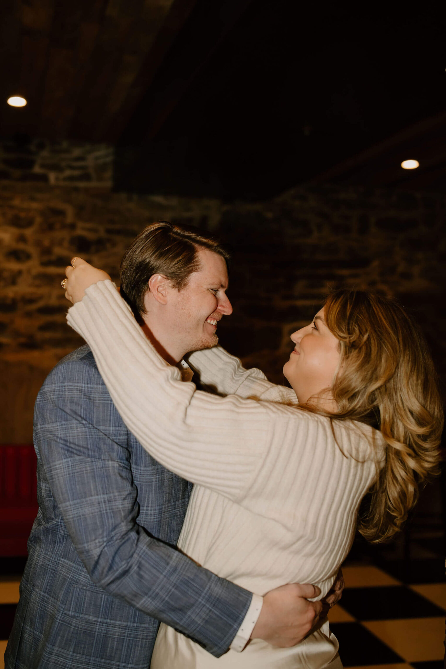a couple embracing, with her arms around his neck, smiling at each other during their engagement session