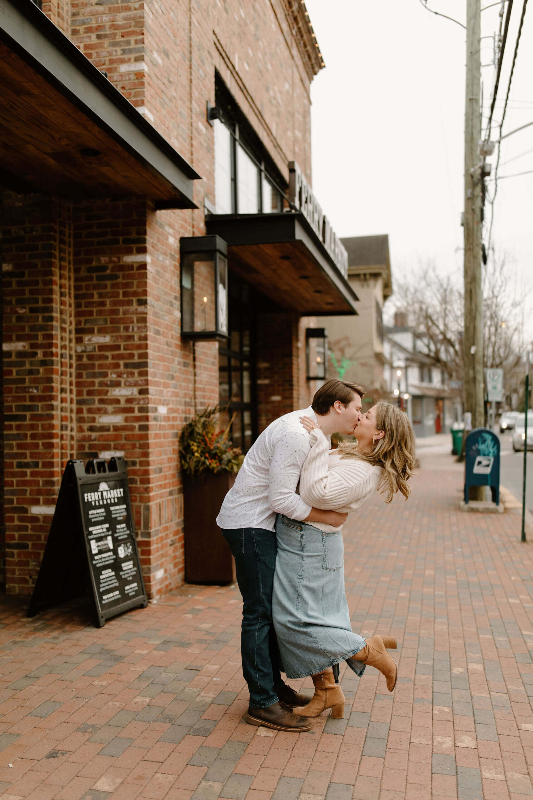 a man kissing his fiance, arms wrapped around her waist and bending her back while she holds his shoulders during their engagement session