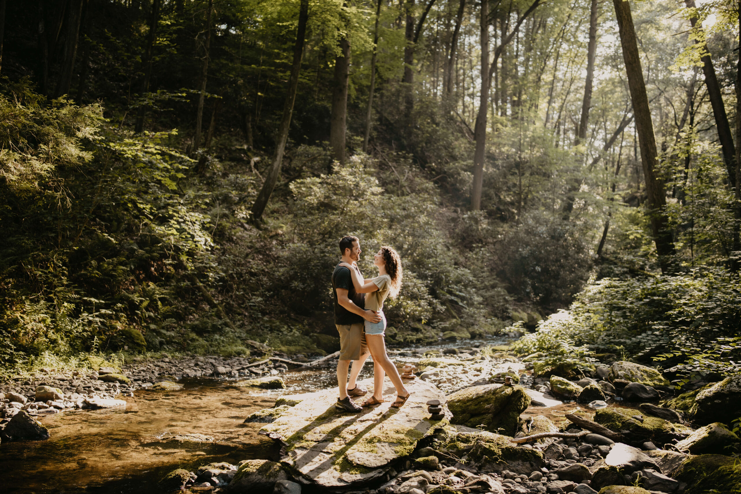 engagement photos in a forest, standing on a large rock in a creek