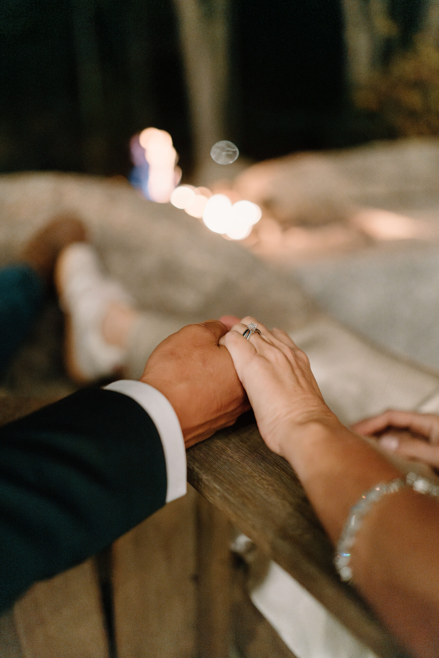 close up image of a bride and groom holding hands, with a fire roaring in the background, the focus on her engagement and wedding rings, after Pennsylvania elopement