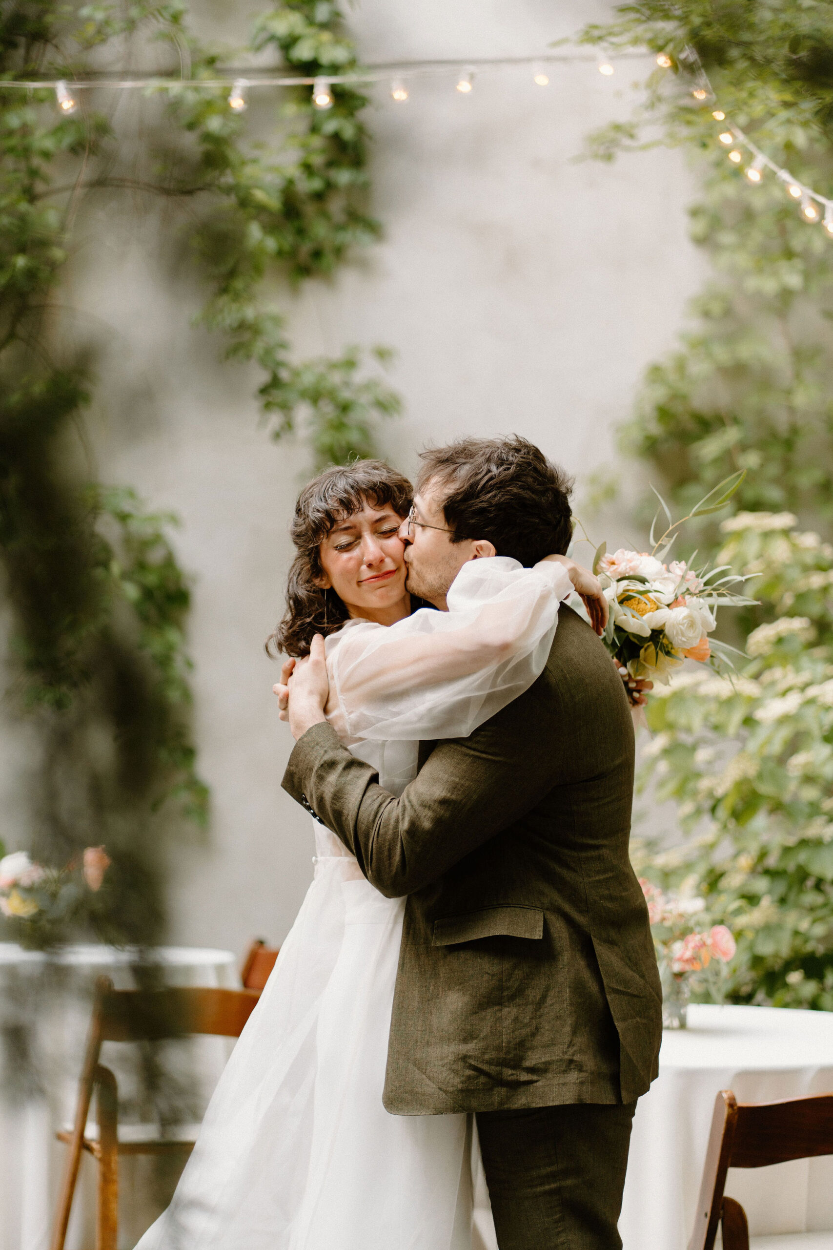 groom kissing bride on the cheek as she cries after their wedding ceremony at the Maas Building