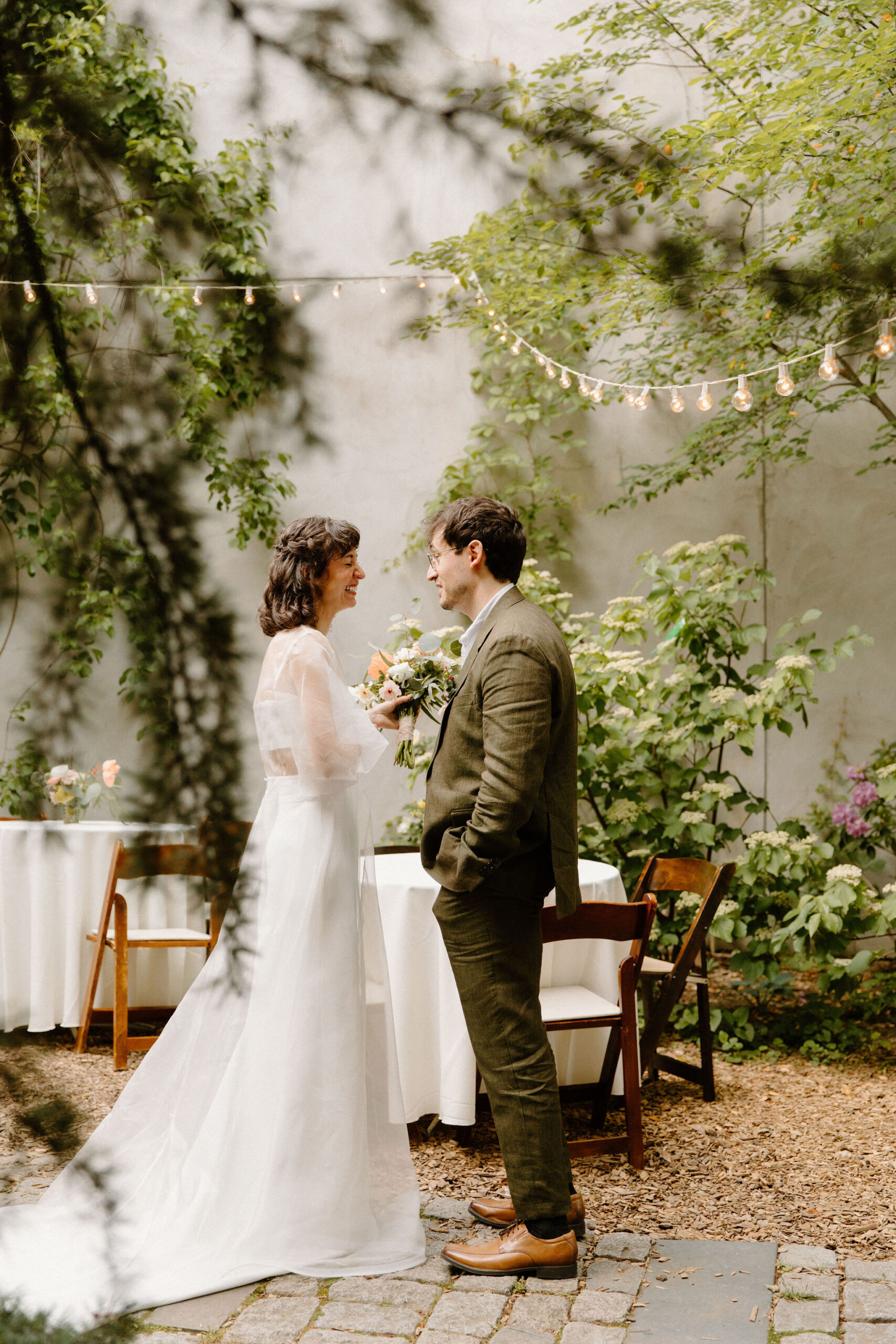 bride and groom taking a private moment to talk after their ceremony in the cocktail hour space, within a lush green cobblestone courtyard during their wedding at the Maas Building