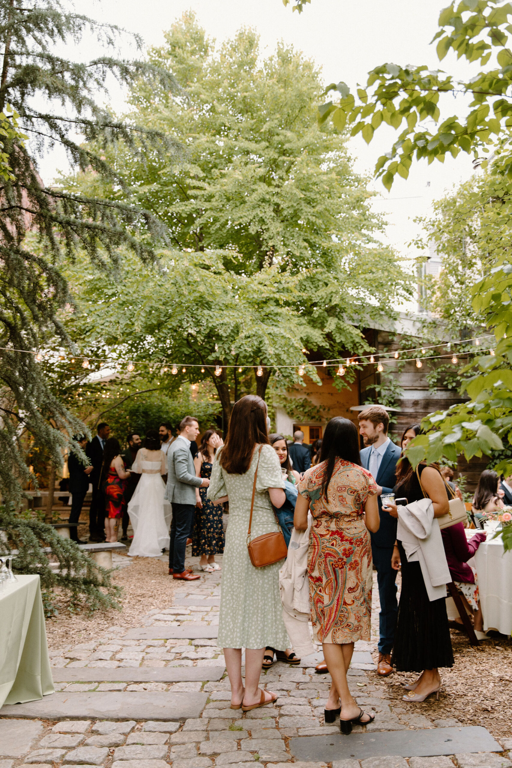 wide image of guests mingling in a courtyard cocktail hour during a spring wedding at the Maas Building