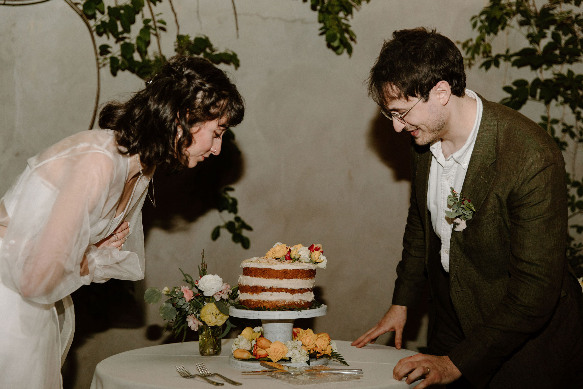 bride and groom looking down at their homemade carrot wedding cake, at the Maas Building in Philadelphia