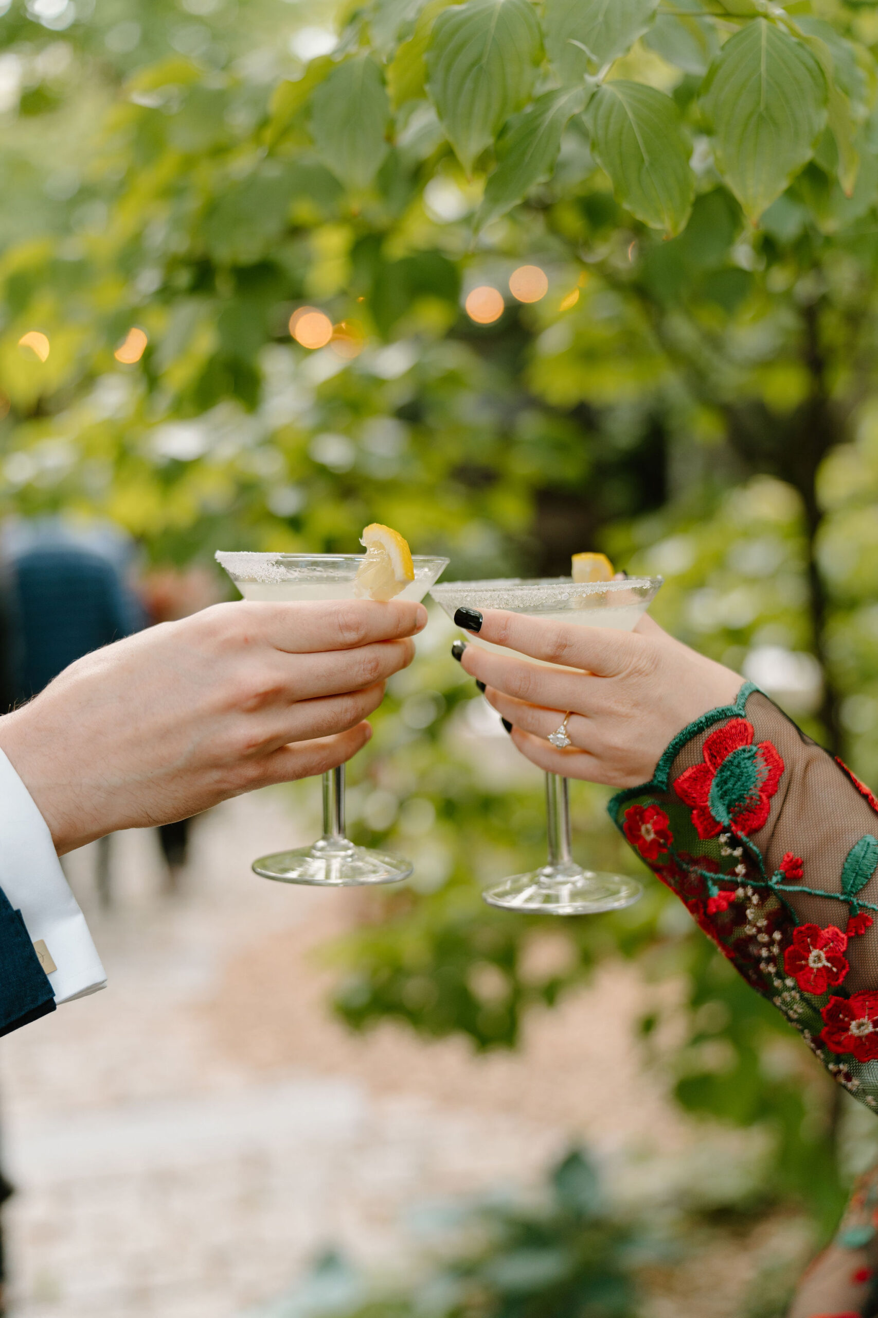 close up of two guests toasting their martini glasses together during a spring wedding at the Maas Building