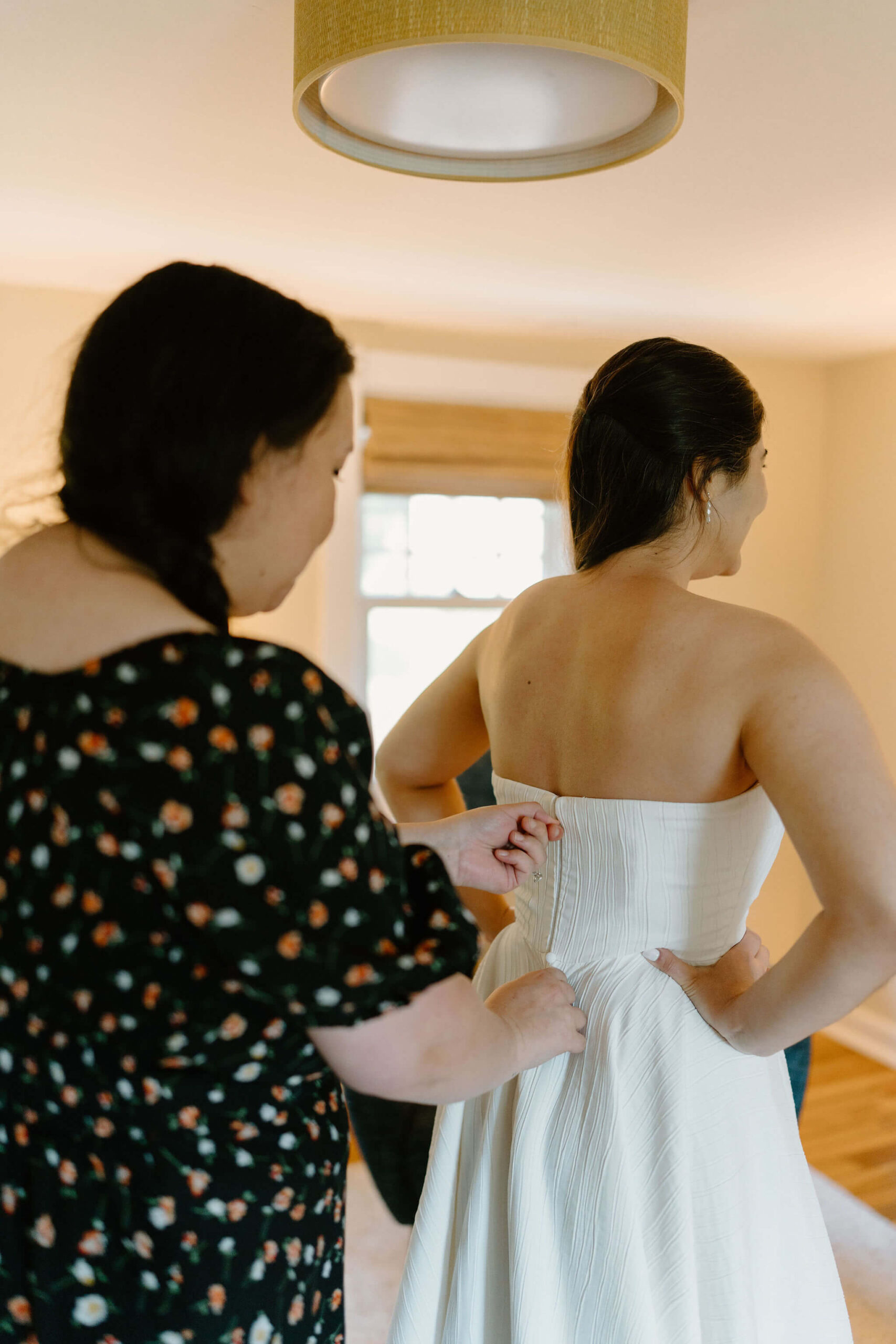 bride's friend (black floral dress) zipping up the bride's strapless wedding gown before she elopes in Pennsylvania