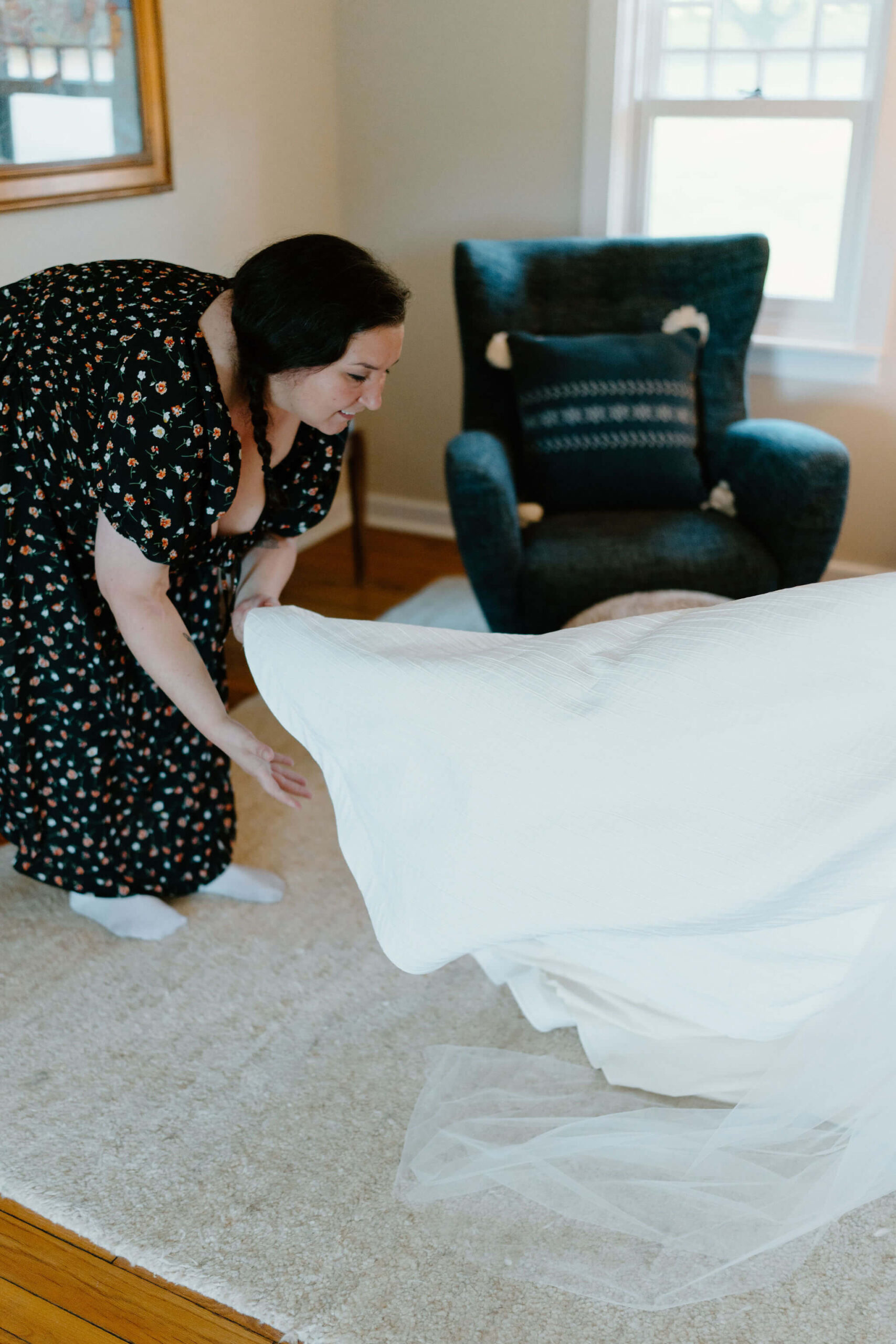 bride's friend bending over to fluff the train of her elopement gown
