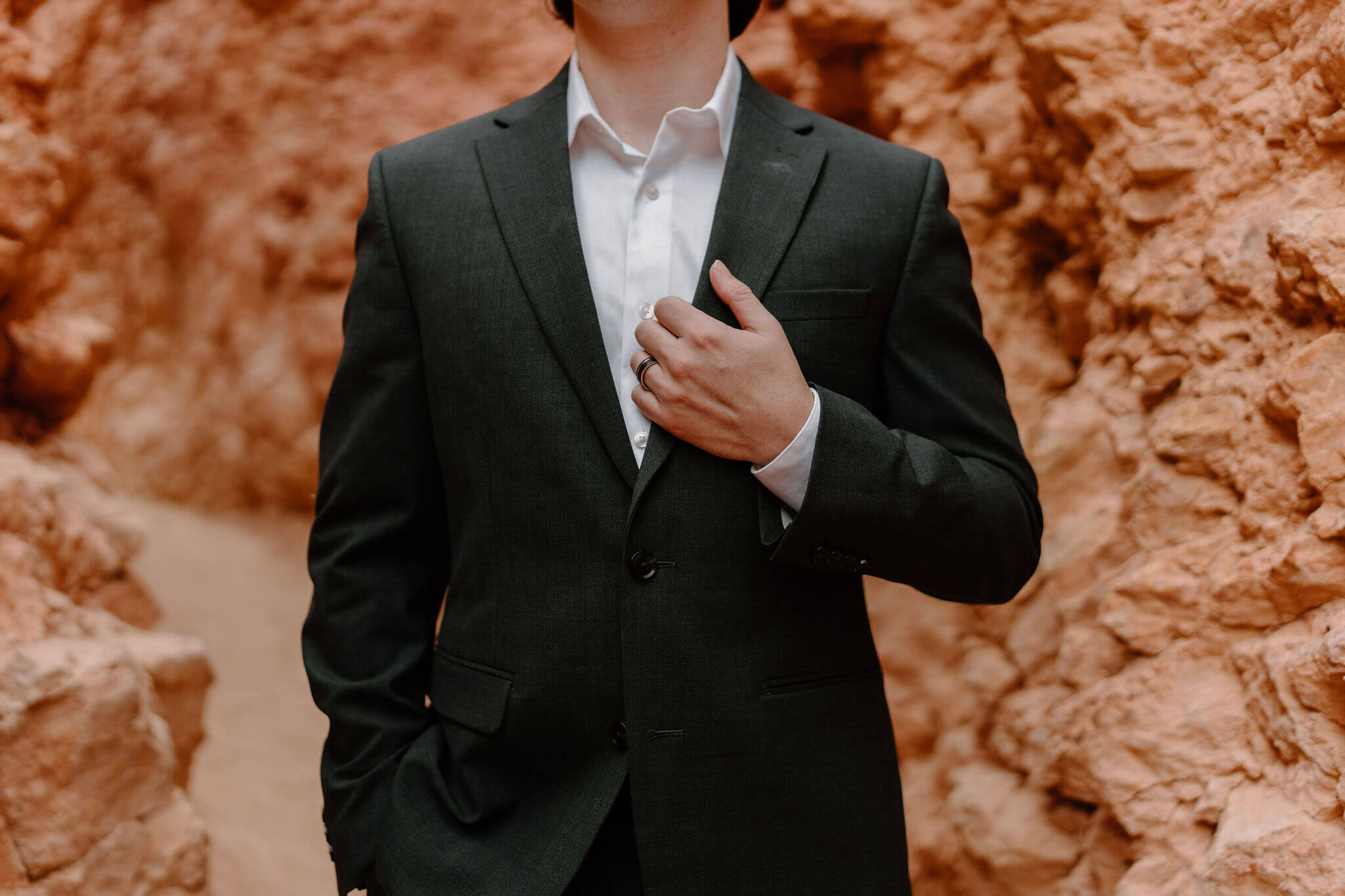close up image of groom holding his lapel with his left hand, showing his wedding band