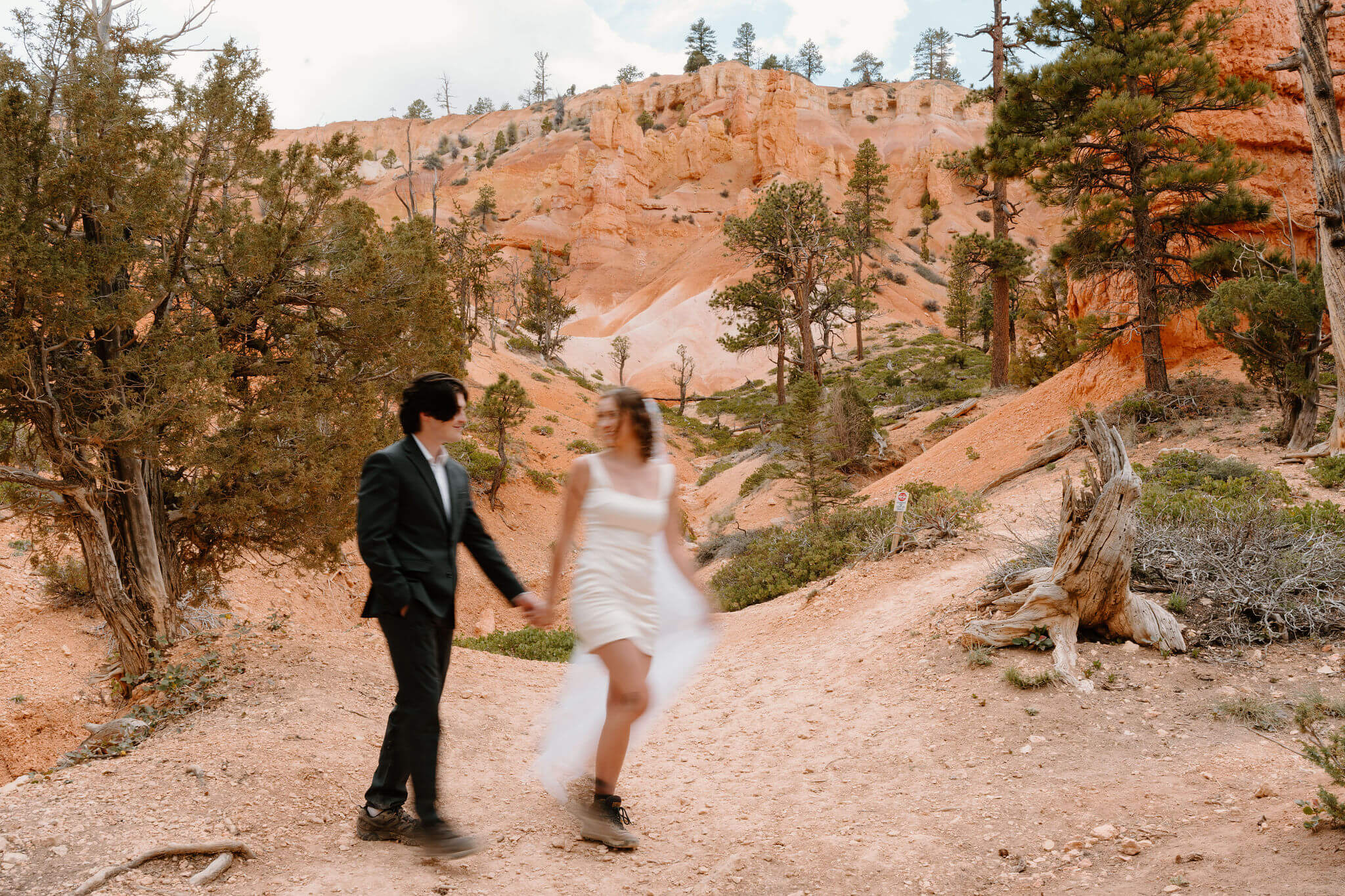 motion blur image of bride and groom holding hands and walking through a desert canyon