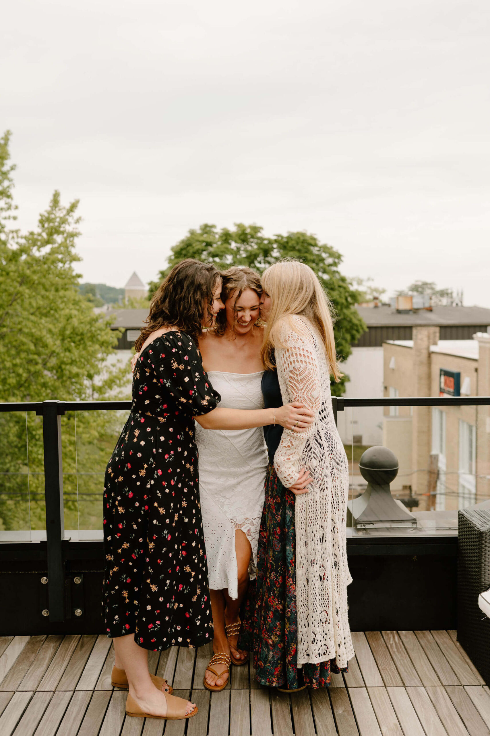 bride with her mother and sister, all hugging and laughing