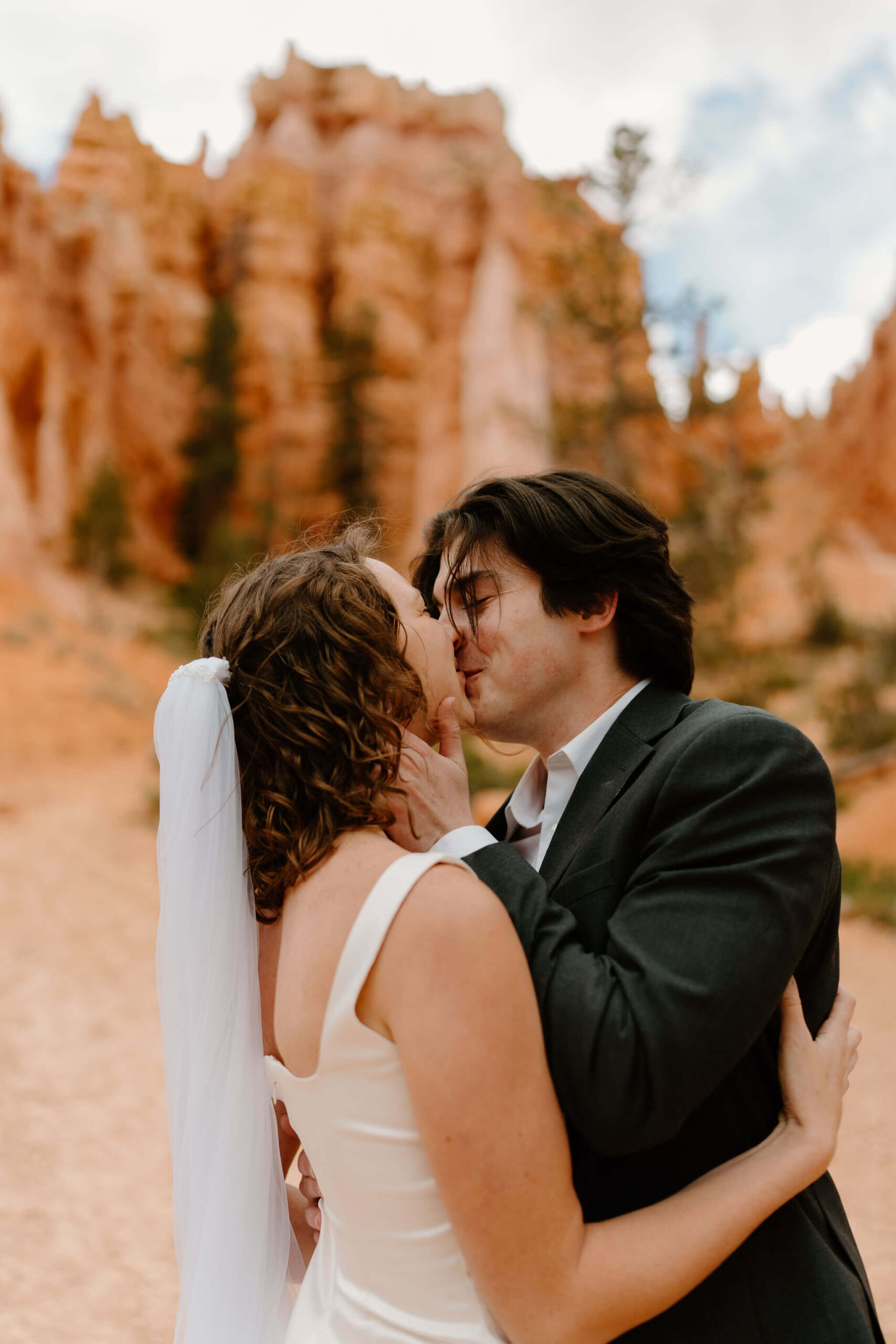 close up of groom holding bride's face, kissing her in front of the hoodoos of Bryce Canyon National Park
