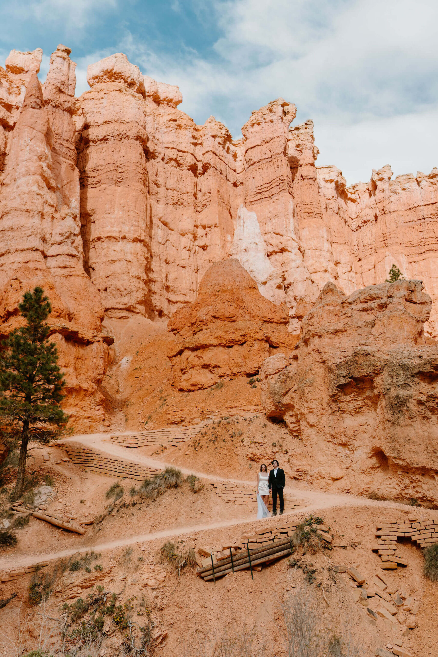 bride and groom posing stoically next to each other on a switchback trail on the Queen's Garden trail at Bryce Canyon National Park