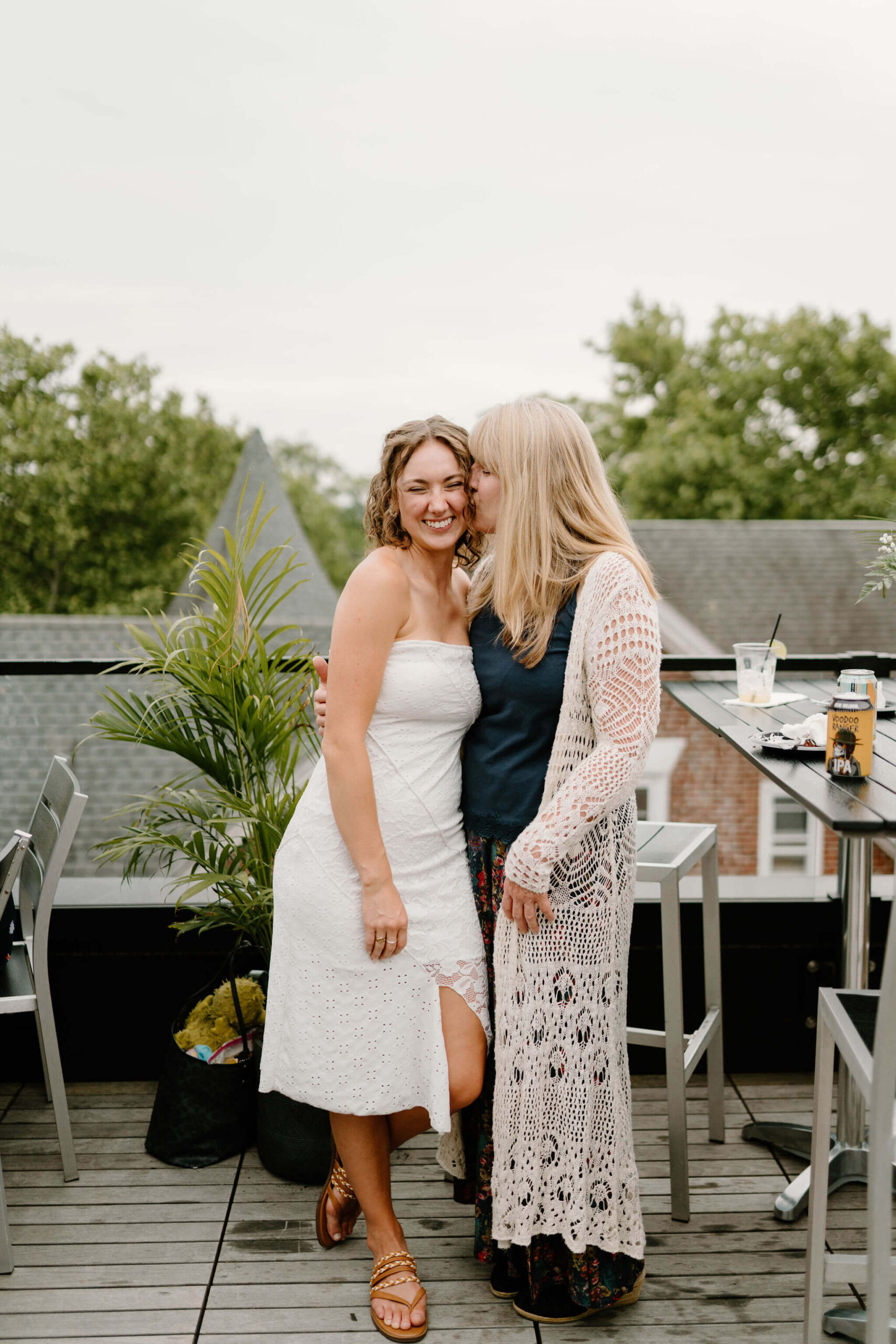 bride's mother kissing the bride on the cheek, both smiling
