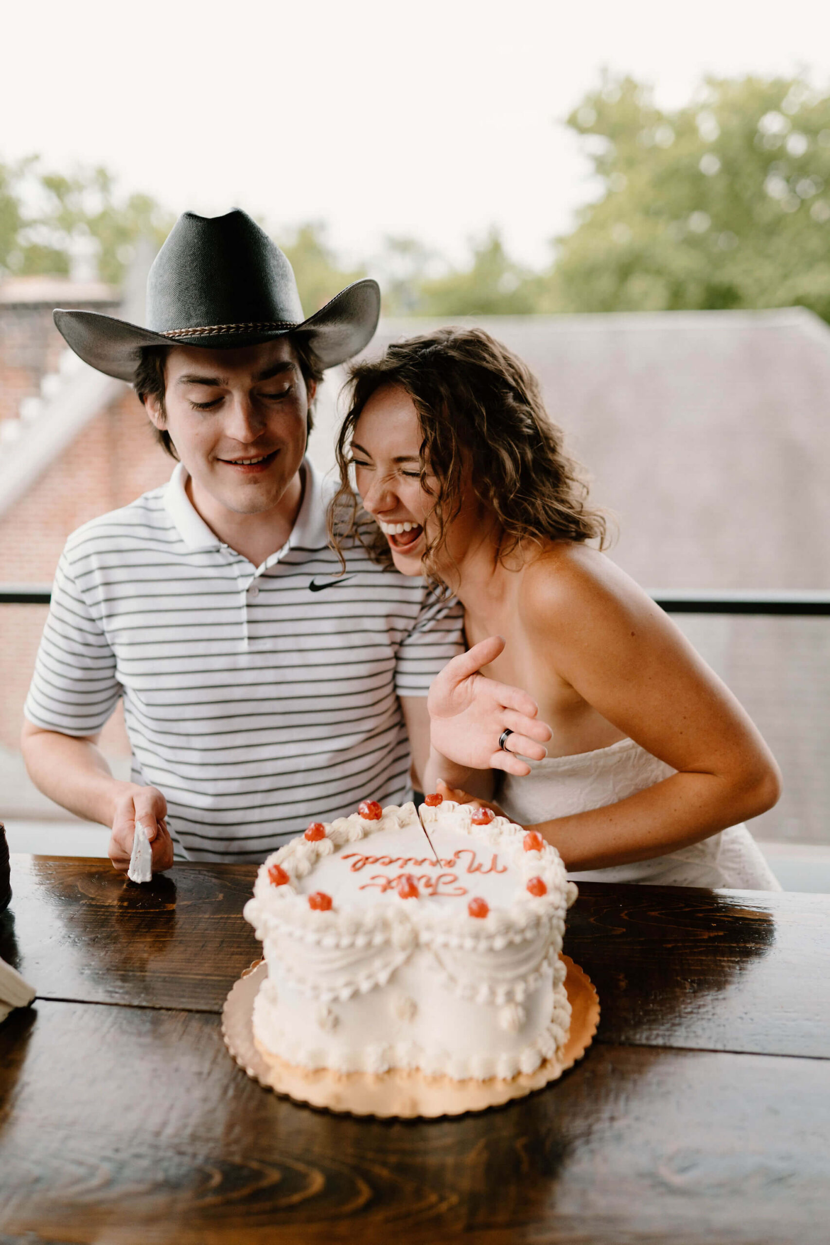 bride and groom laughing while cutting their wedding cake