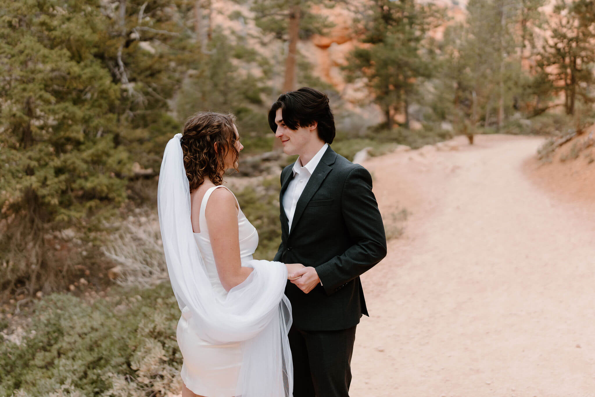 bride and groom smiling at each other and holding hands