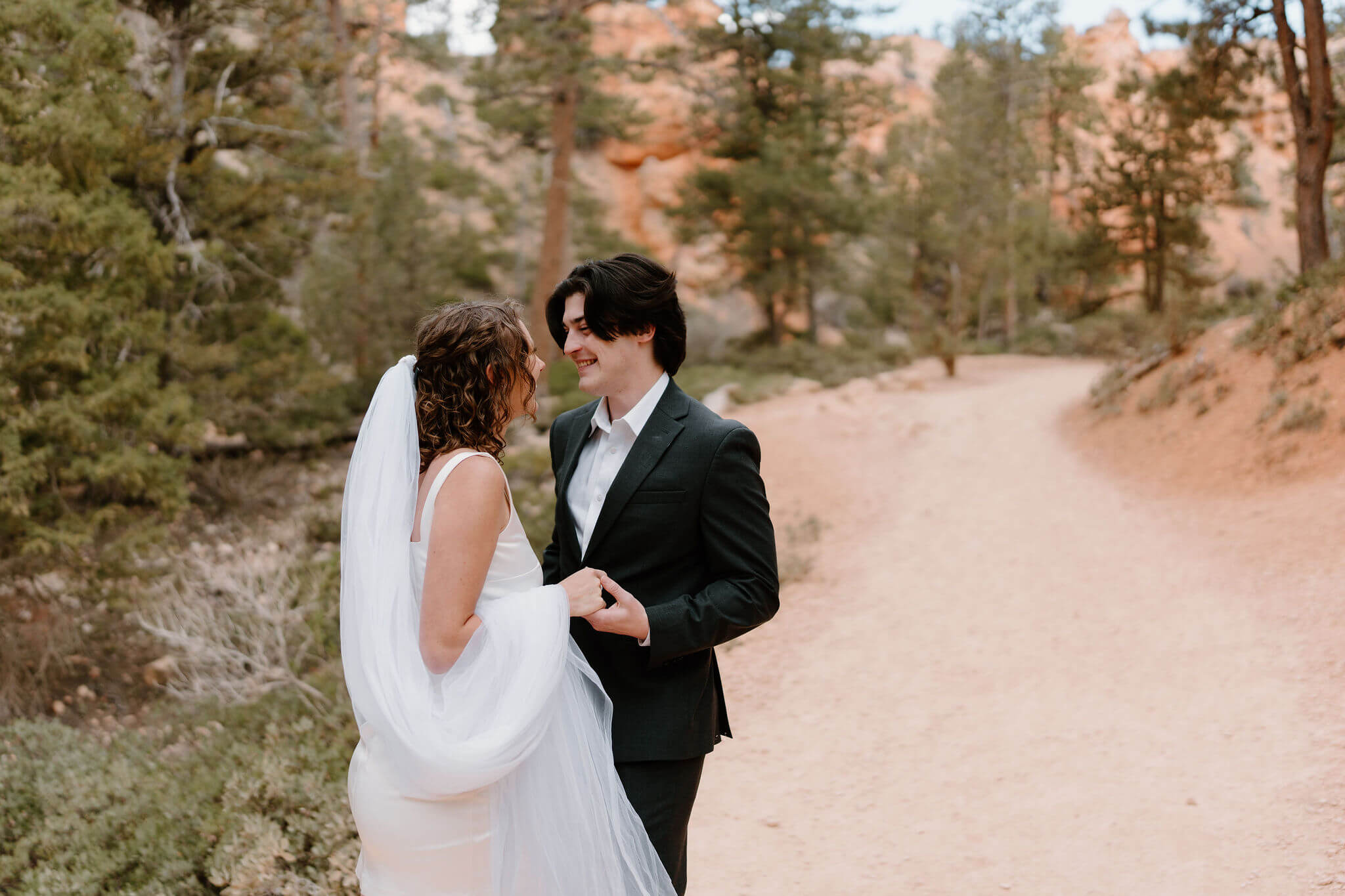 bride and groom smiling at each other and holding hands
