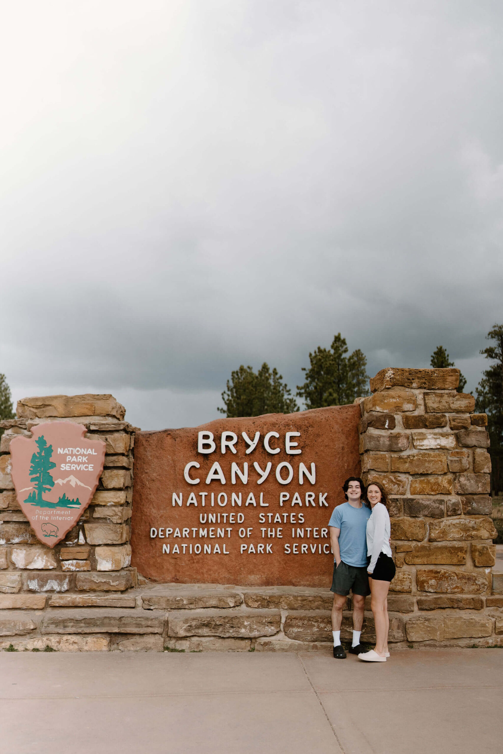 man and a woman smiling in front of the Bryce Canyon National Park welcome sign