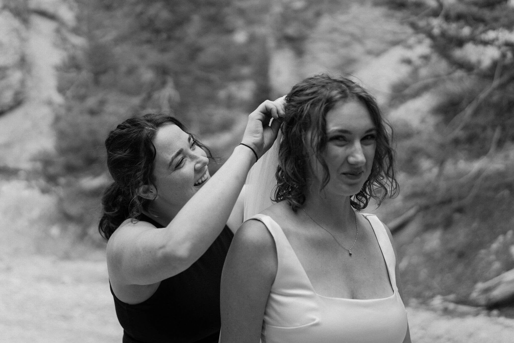 bride's sister fixing the bride's veil, both smiling