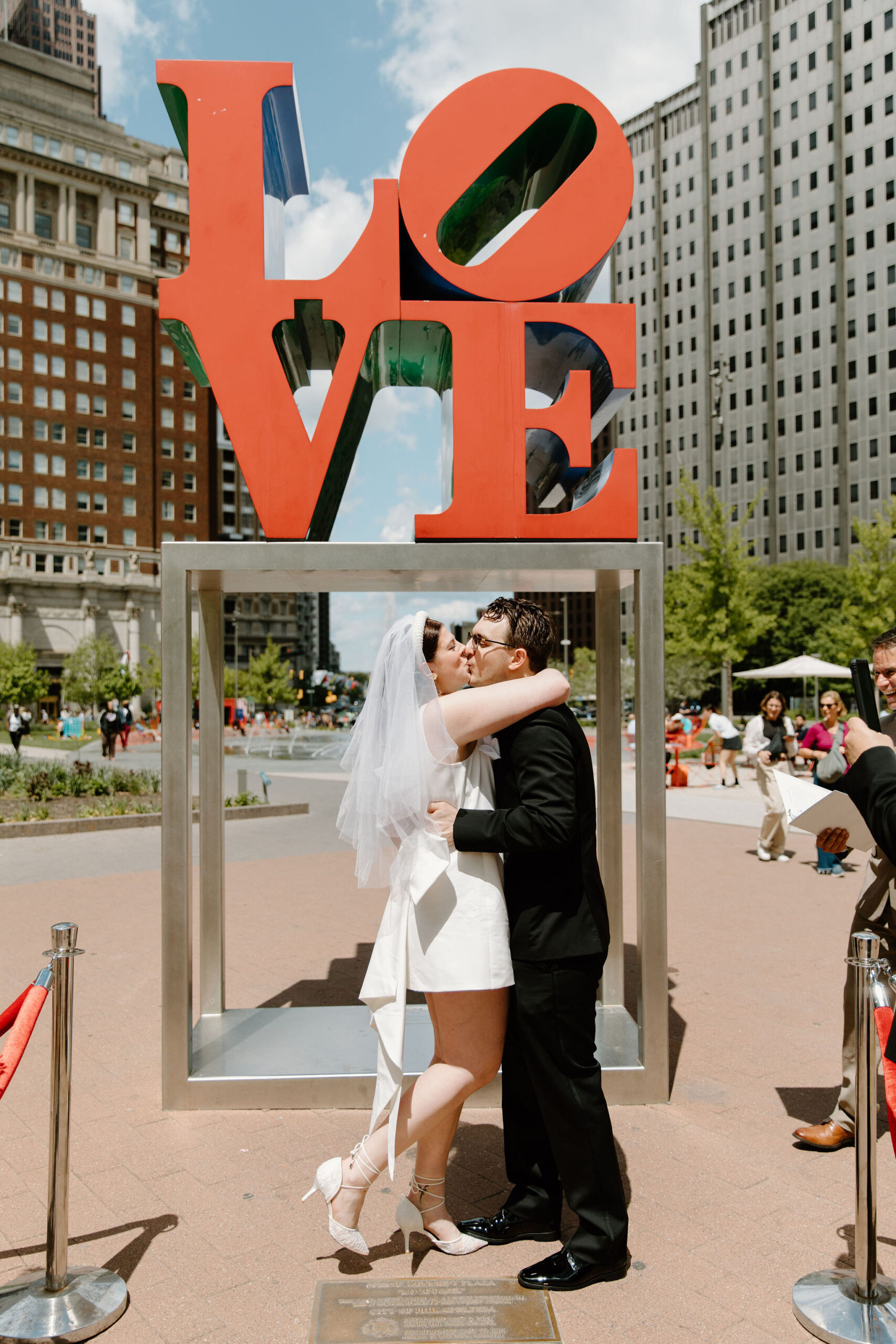 bride and groom having their first kiss at the end of their wedding ceremony during their intimate wedding at Love Park in Philadelphia