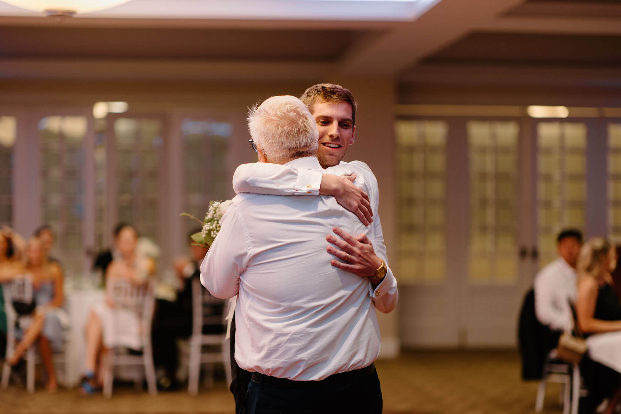 groom hugging his father after giving a speech at his wedding reception
