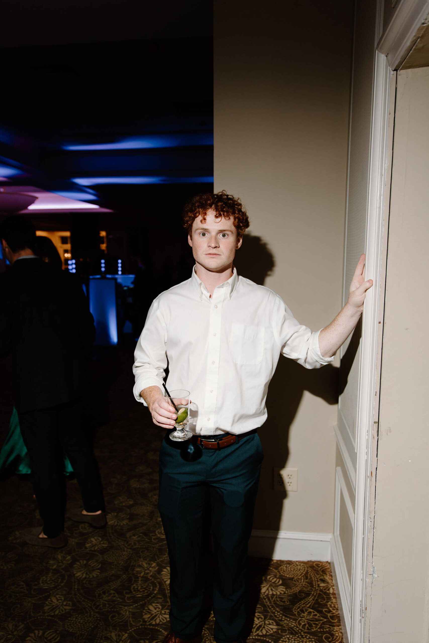 wedding guest posing for the camera while leaning on the wall, a deadpan straight face