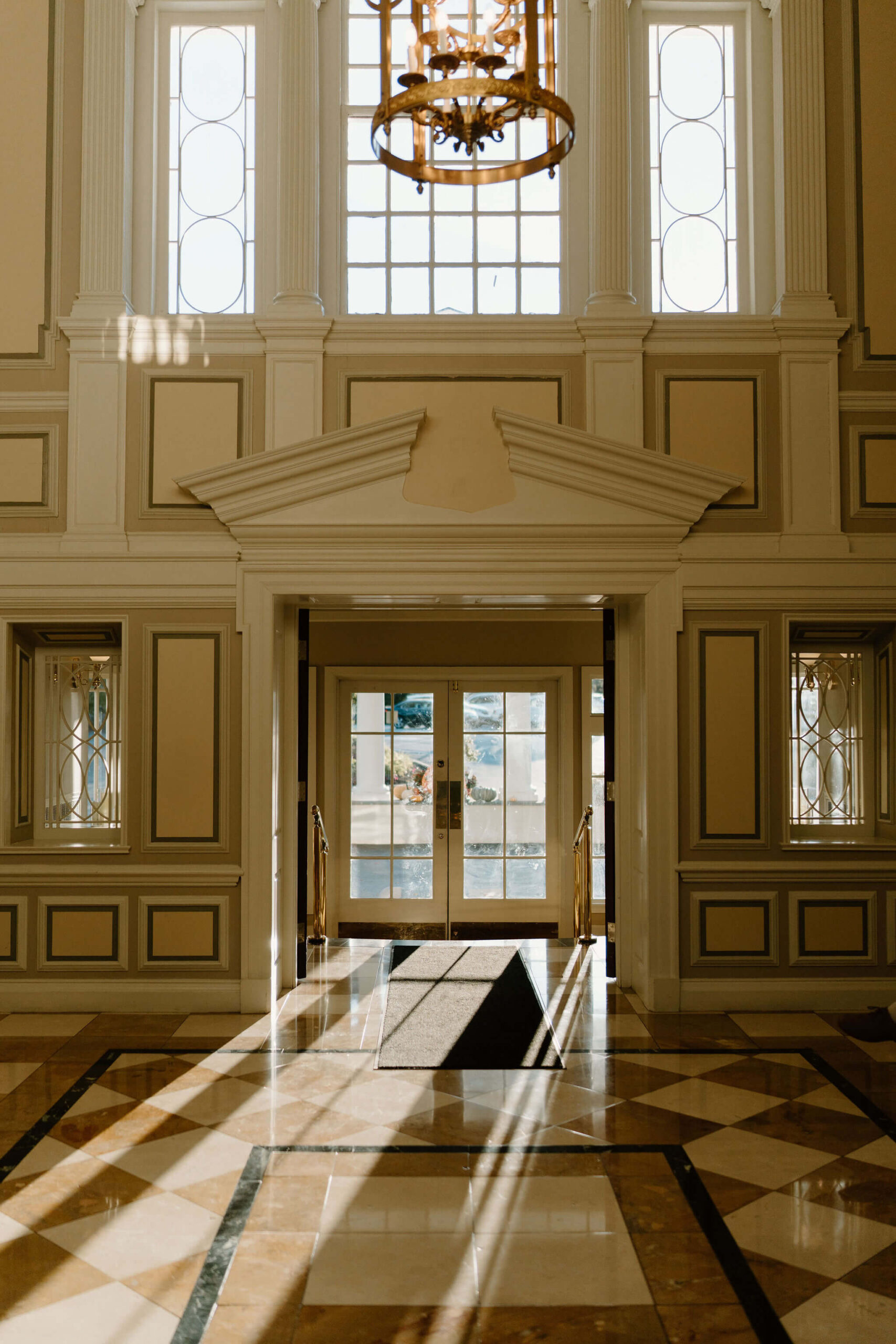 Clubhouse entryway with sunlight streaming in through large windows, casting interesting shadows on a tiled floor
