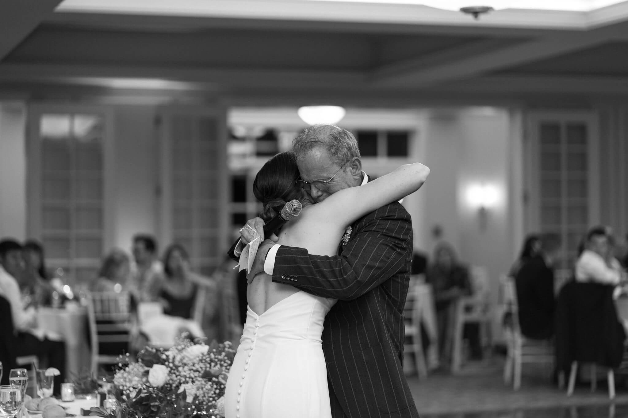 bride hugging her father after giving a speech at her wedding reception