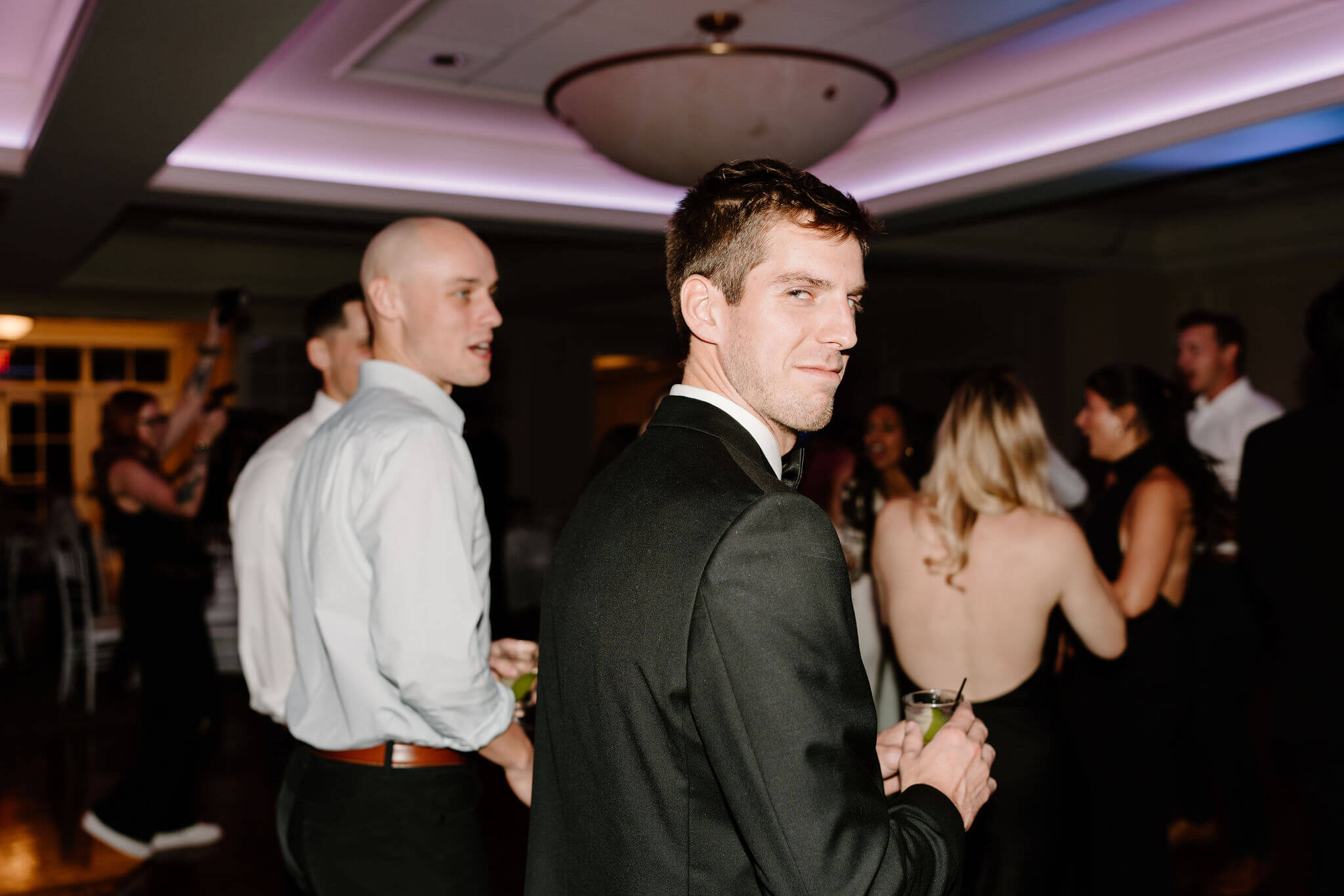 groom smiling softly back toward the camera during the wedding reception