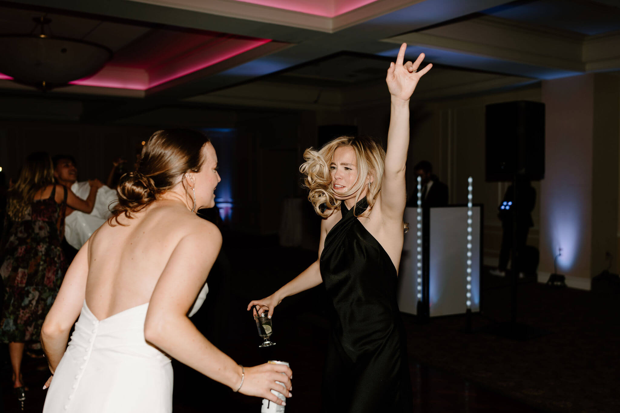 bride and her sister dancing and jumping together on the dance floor at her wedding reception