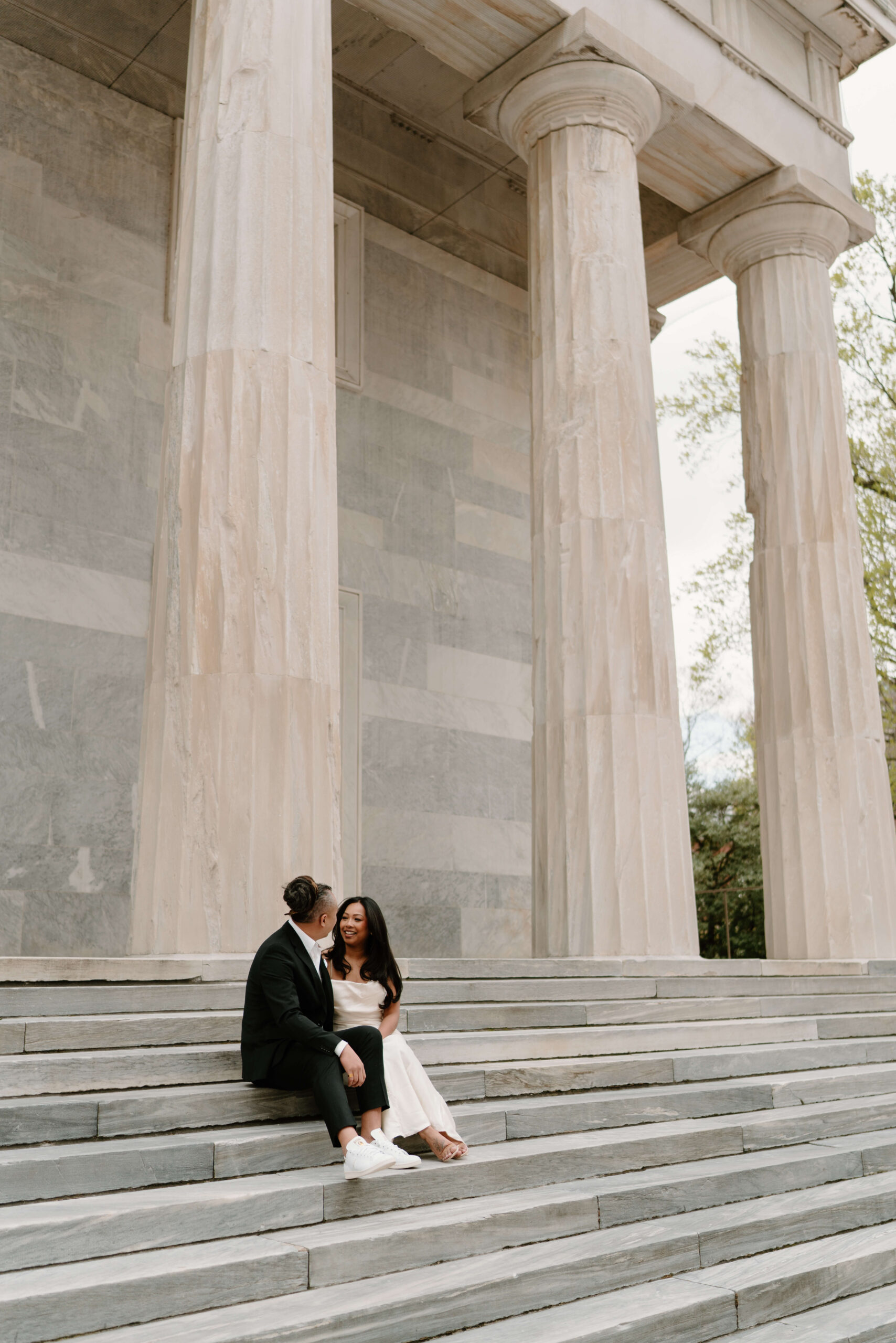 Engagement pictures of a man and a woman sitting on the steps of the Second Bank in Philadelphia, Pennsylvania