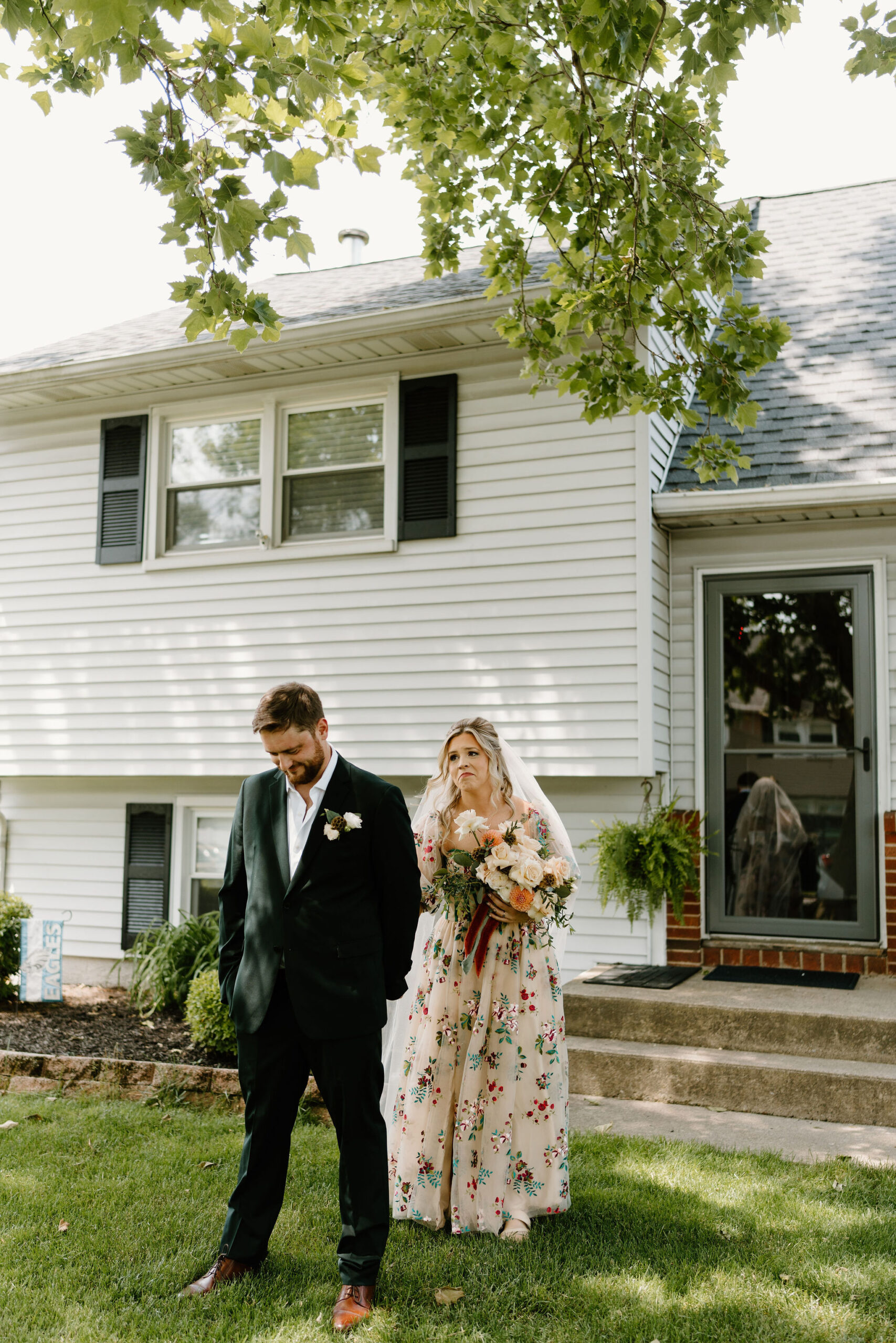 bride in a colorful wedding dress approaching groom for their first look on their wedding day, reaching out to hold his hand while his back is to her
