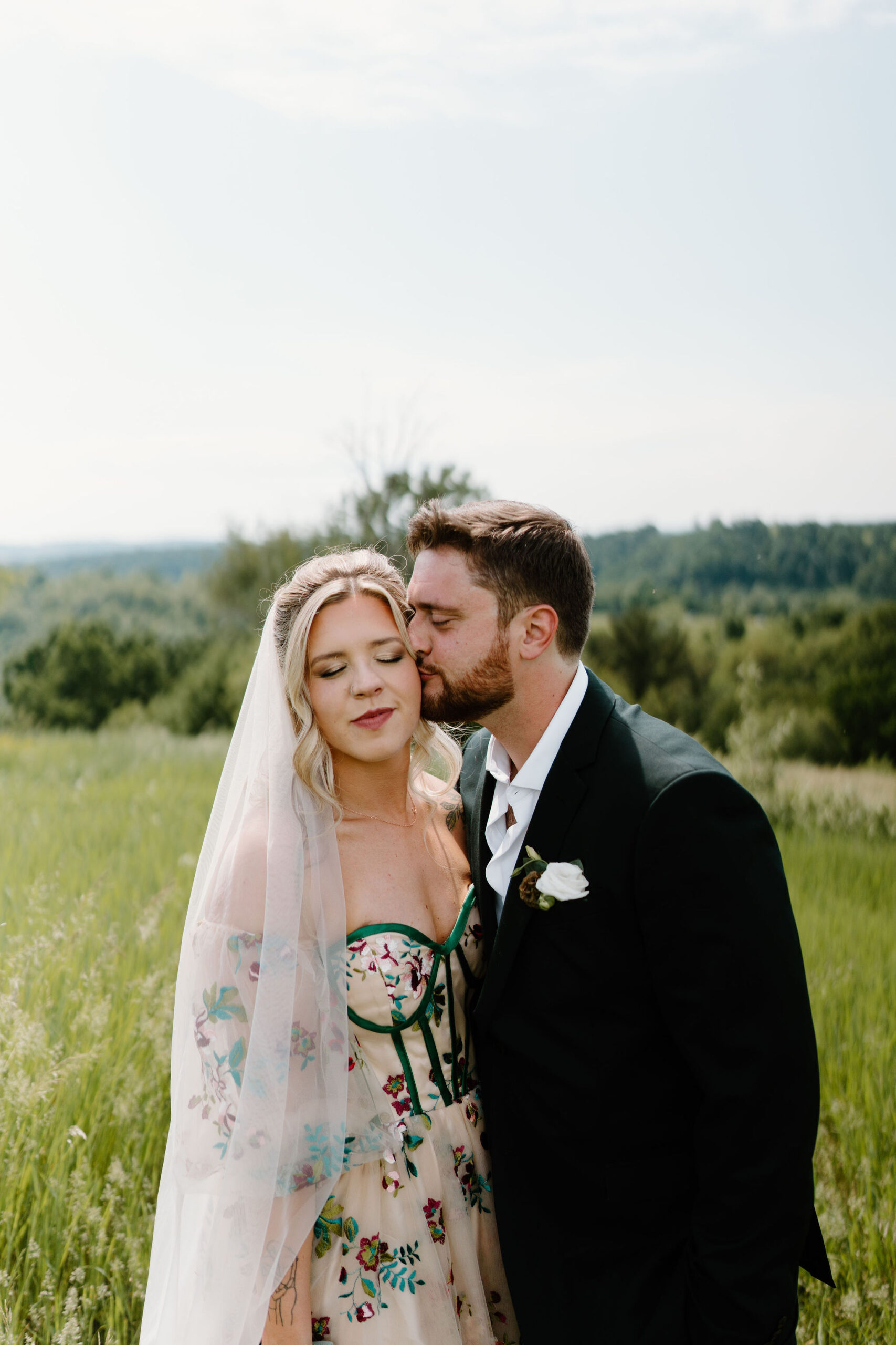 groom kissing his bride on the cheek on a sunny day