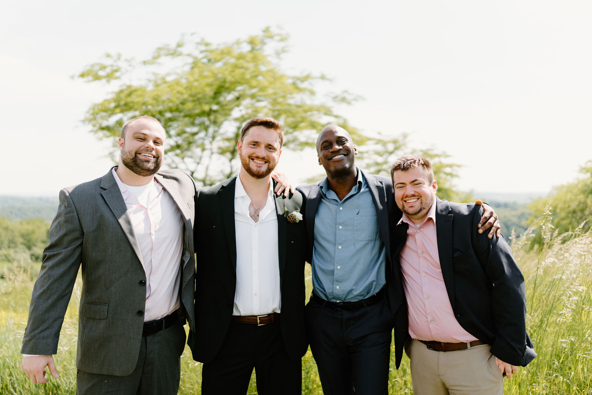 groom and his groomsmen smiling with arms around each other