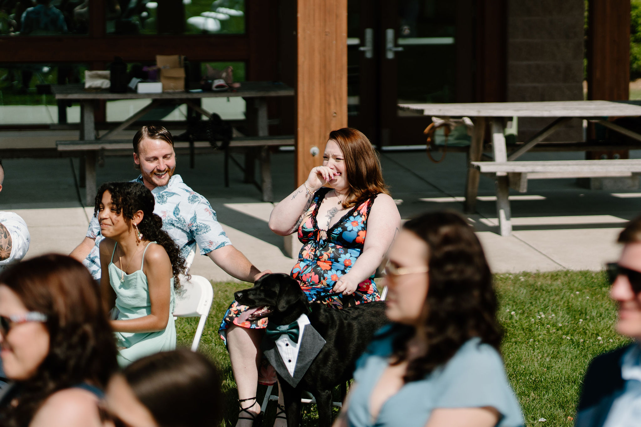 sister of the bride sitting in her chair, holding one of their dogs, while crying during the wedding ceremony