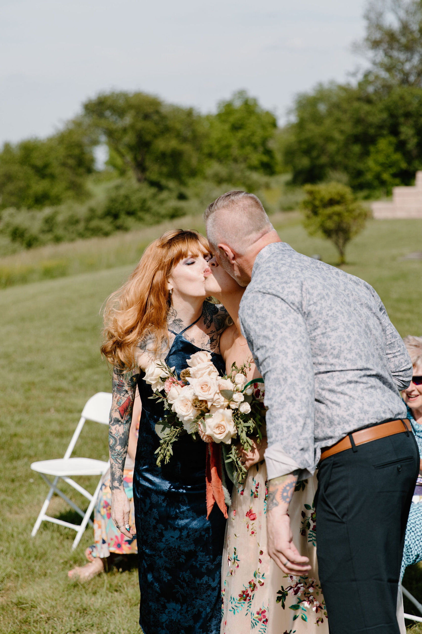 bride's parents kissing her on the cheek as she arrives at the end of the ceremony aisle
