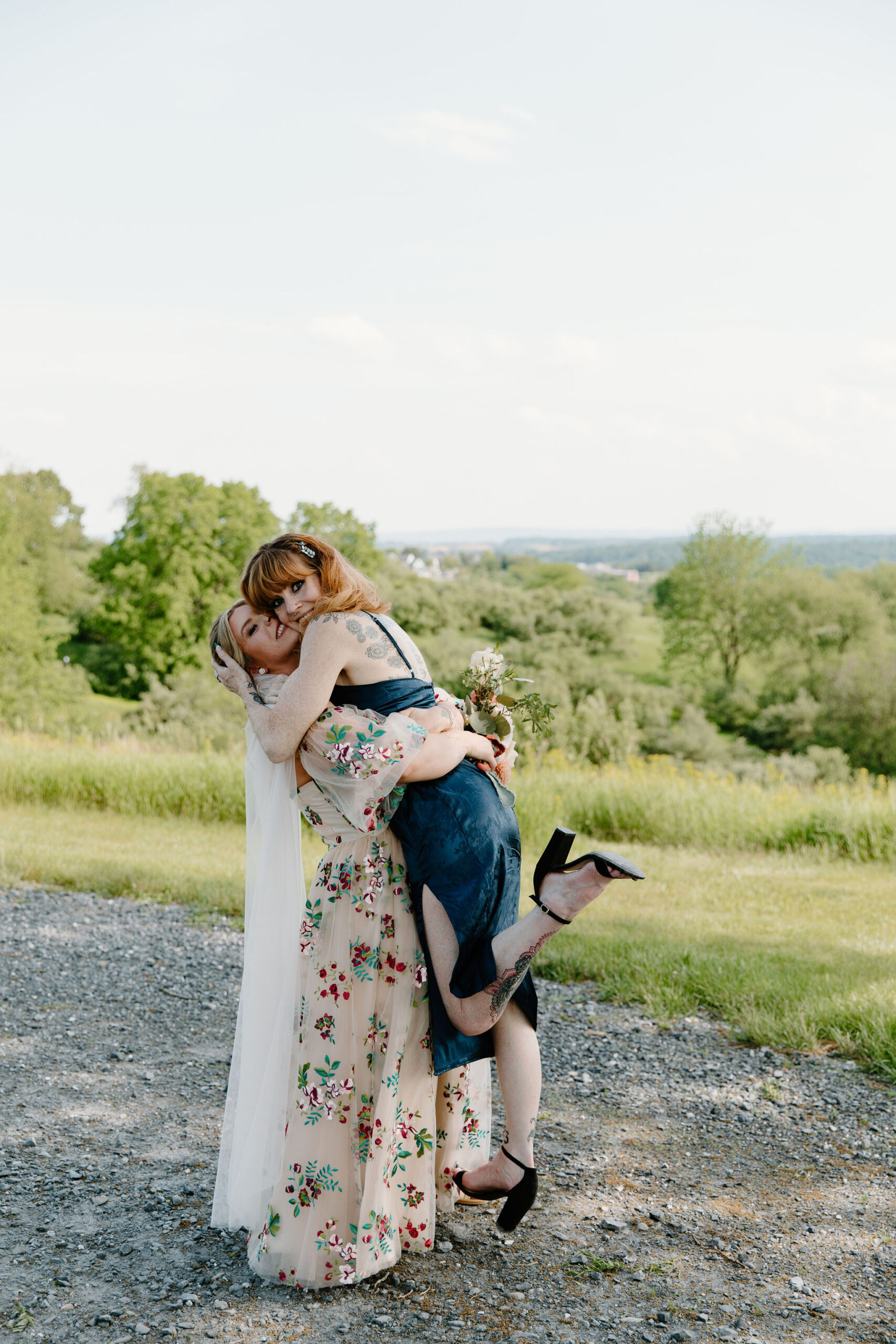 bride lifting up her mother, who pops a heel and smiles at the camera