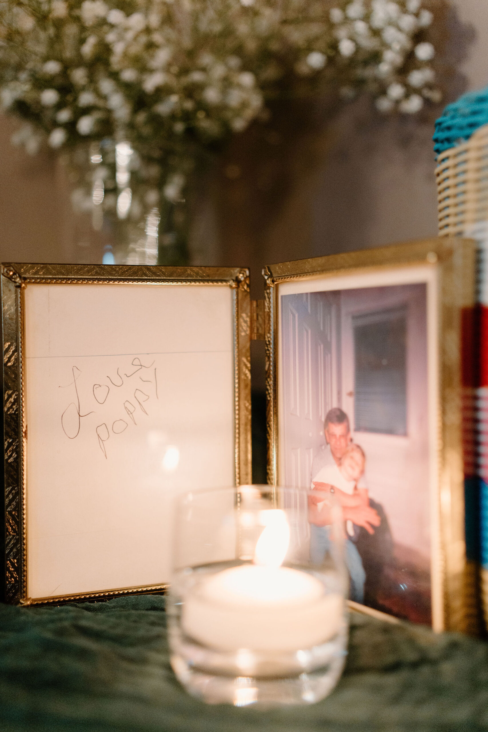 a candle illuminating a photo of the bride as a child with her late grandfather, and a framed card saying "Love, Poppy"