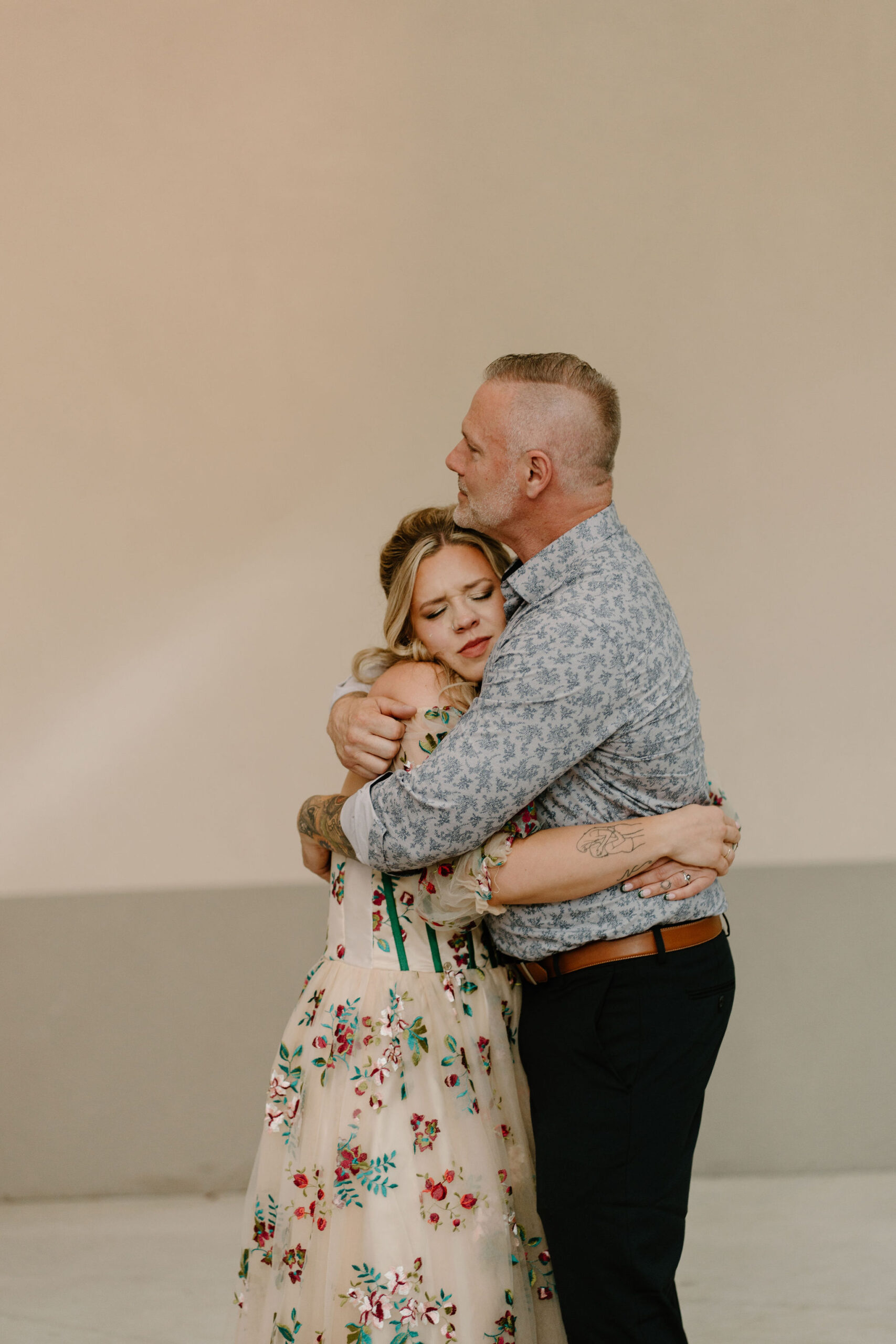 bride closing her eyes emotionally as her father figure holds her for their first dance