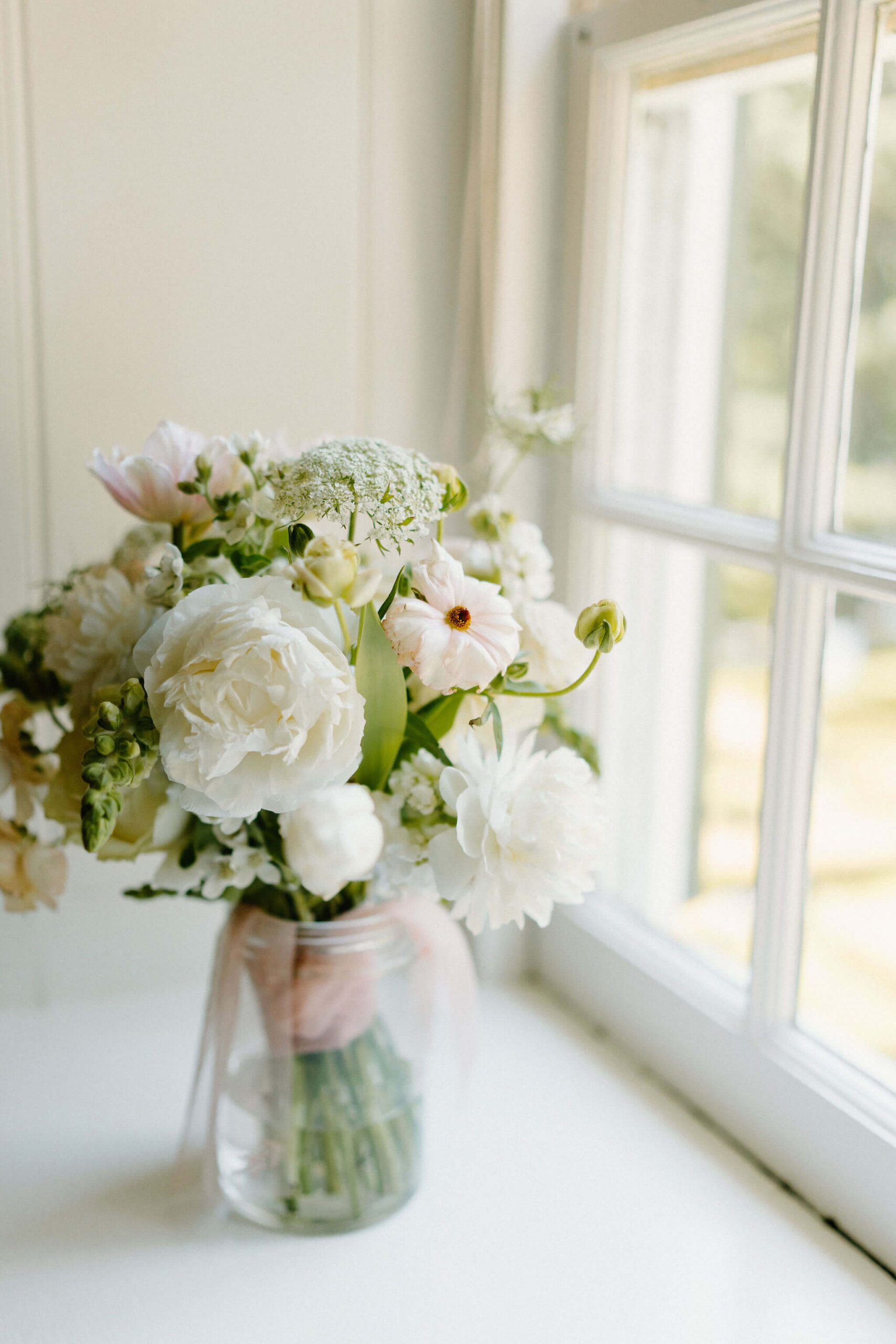bridal bouquet of white and pink flowers in a vase, on a windowsill