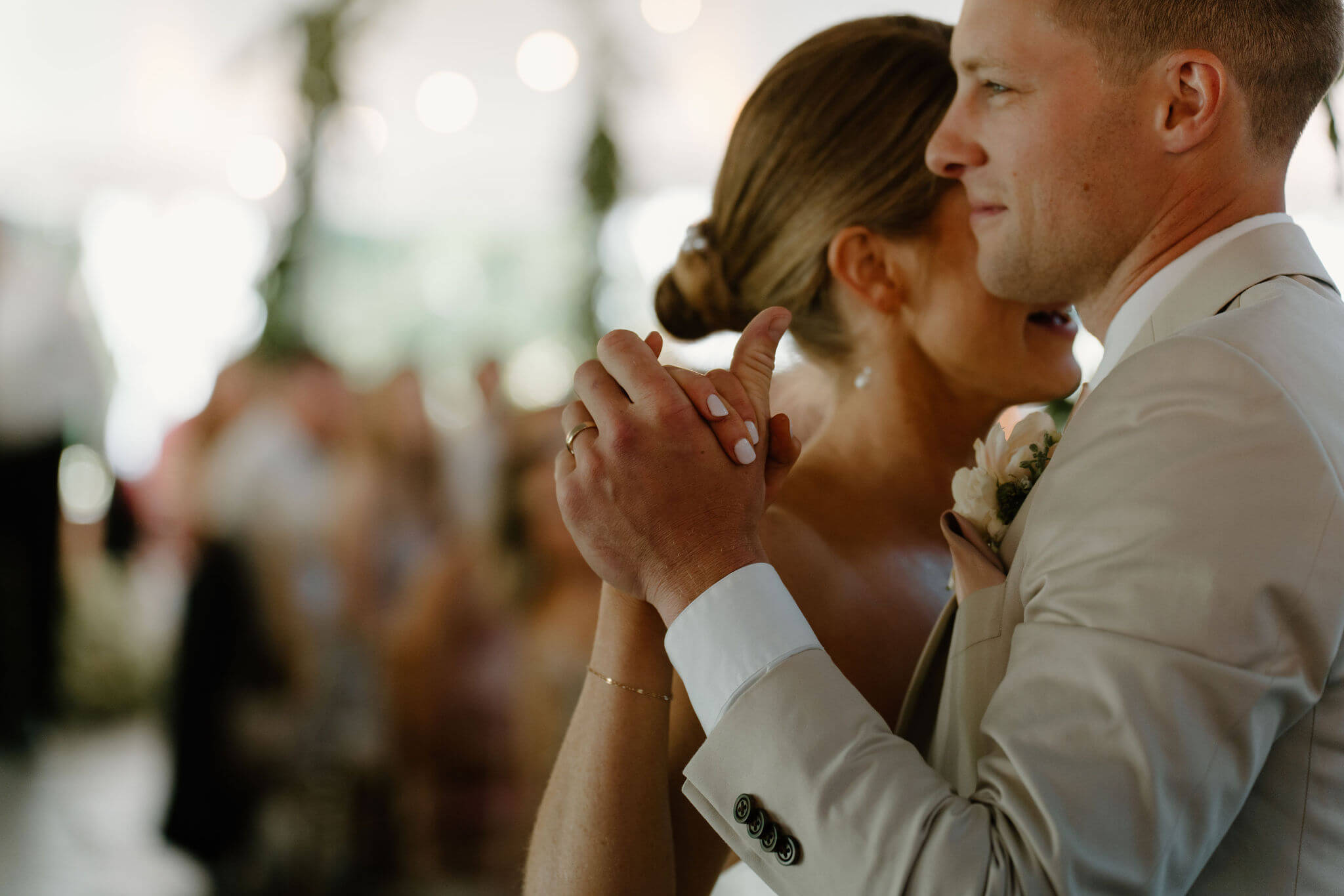 close up of bride and groom's hands, fingers intertwined, during their first dance