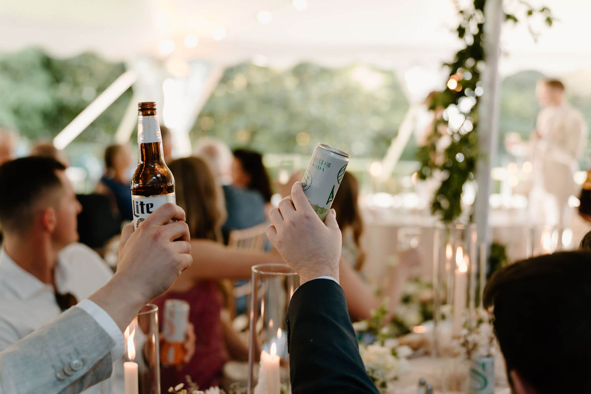 close up of guests toasting speeches during a wedding reception with a beer and stateside can