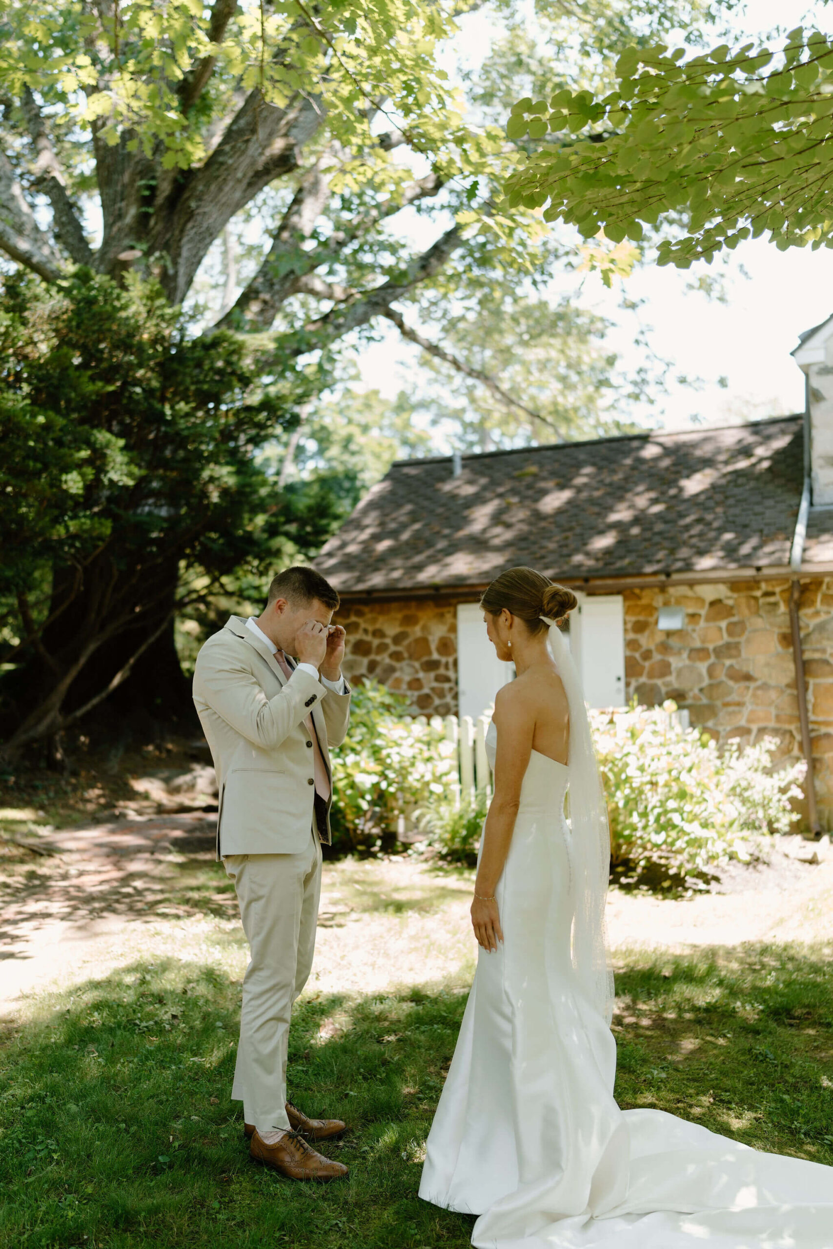 groom (tan suit) crying and wiping his eyes during first look