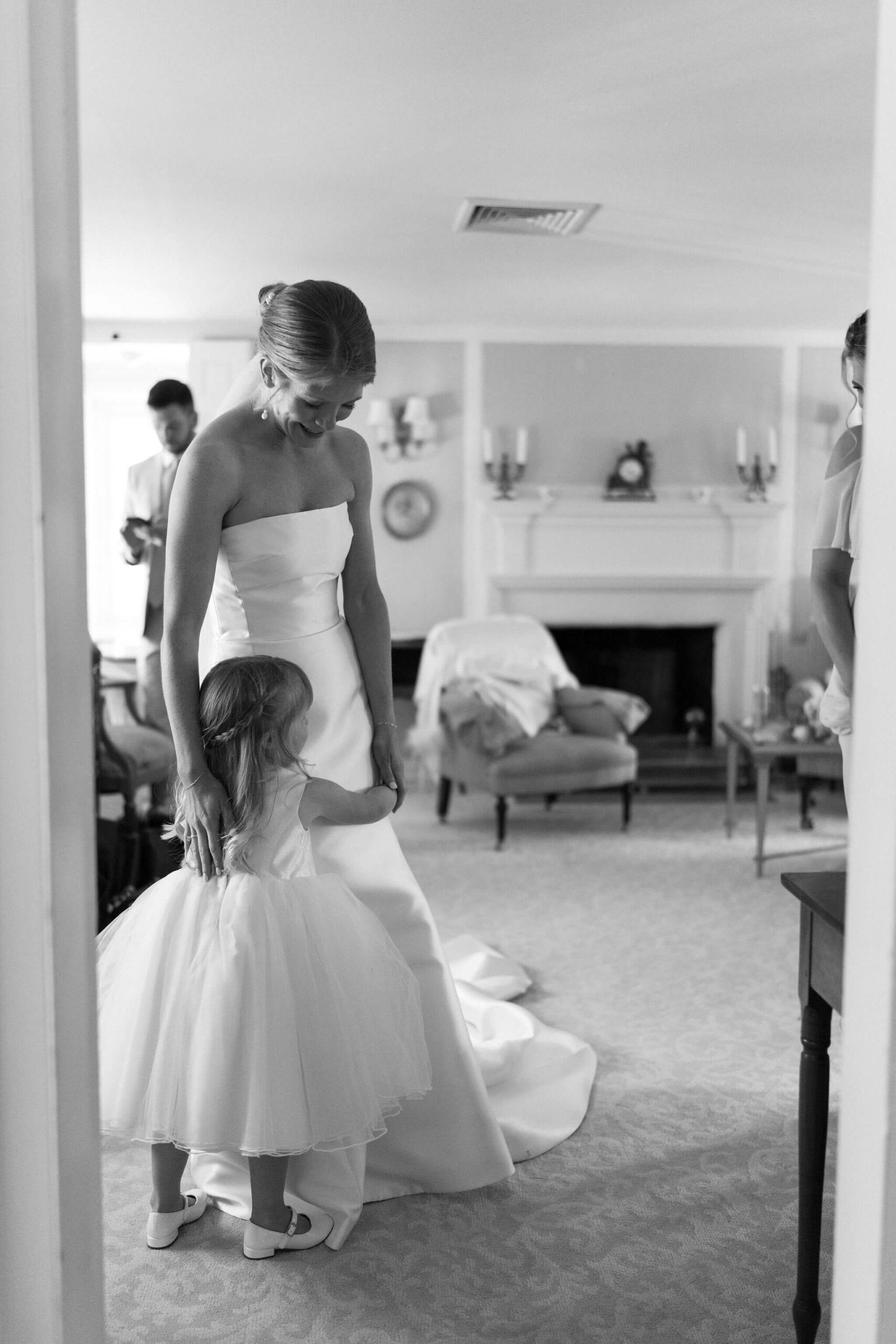 bride standing and hugging a young bridesmaid, also wearing white