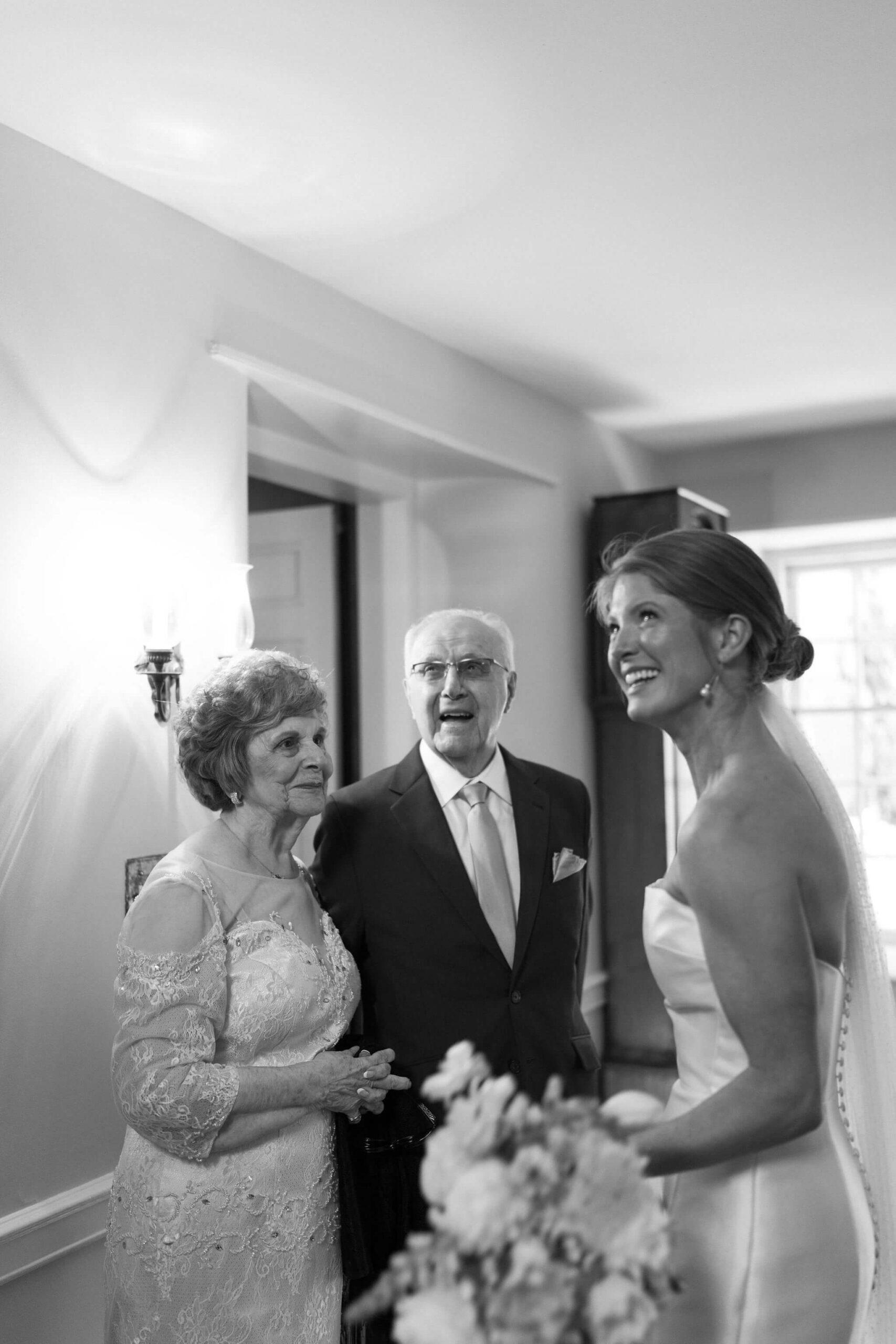 black and white image of bride and her grandparents during a first look, all smiling